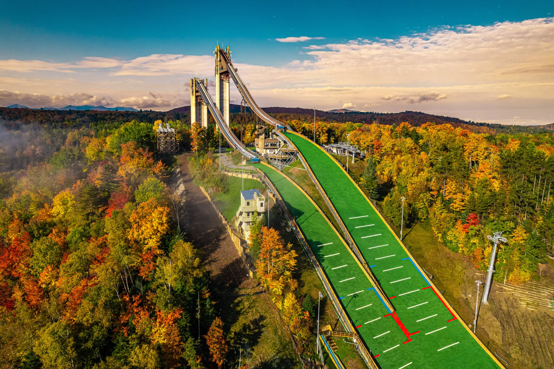 Drone aerial image of Lake Placid's 100 and 128-meter ski jumping towers and runs surrounded by fall foliage