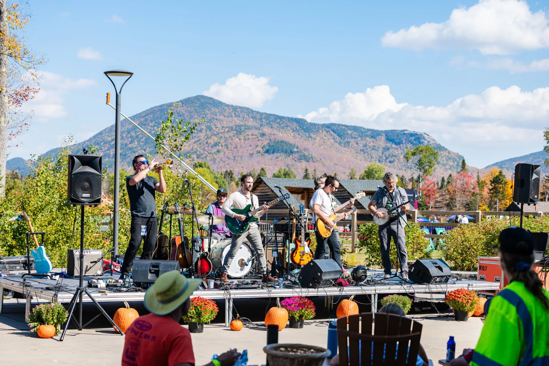 Band plays live music on stage decorated with pumpkins and mums with mountain in background