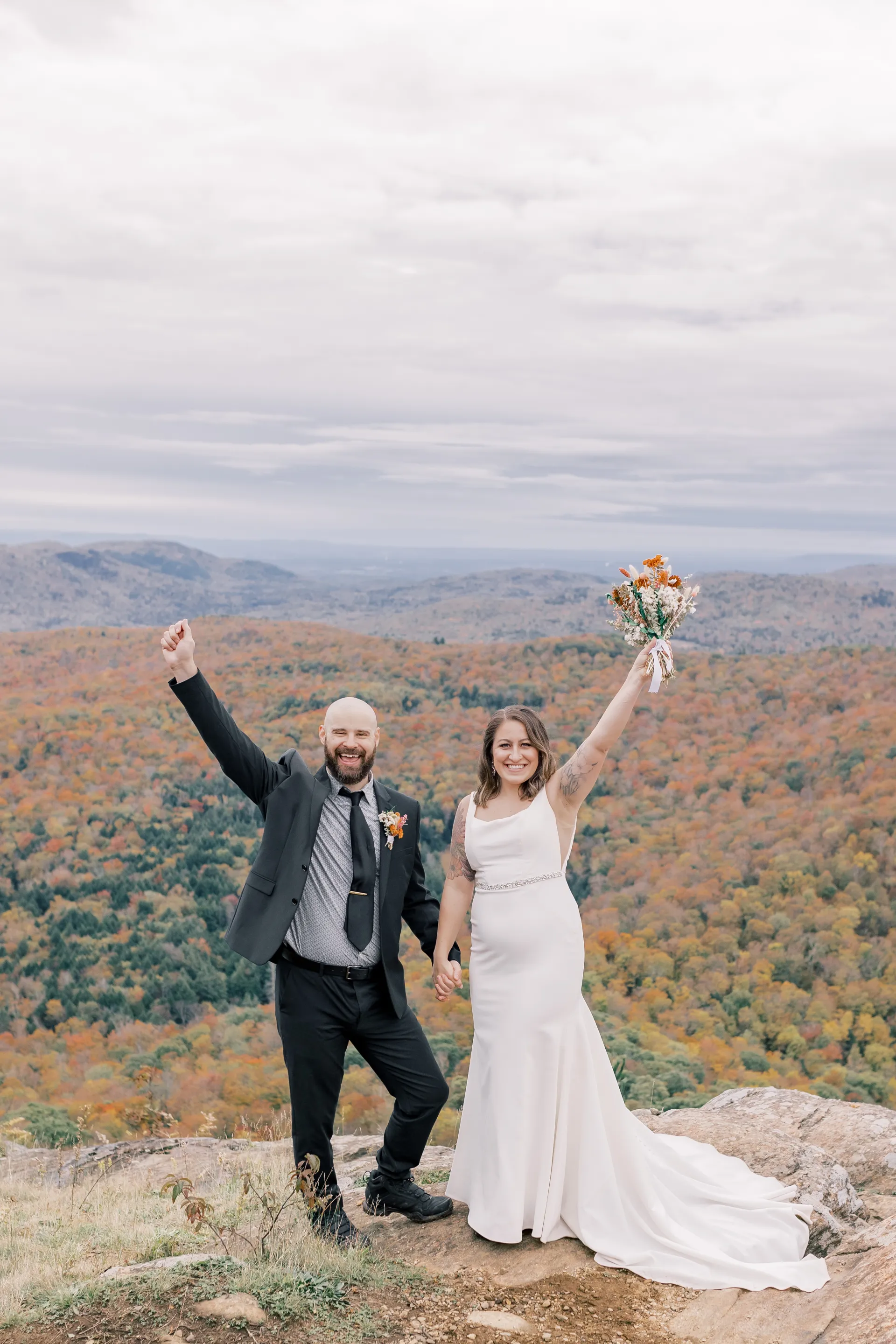 Bride and Groom rejoice and wave arms, smiling at the camera