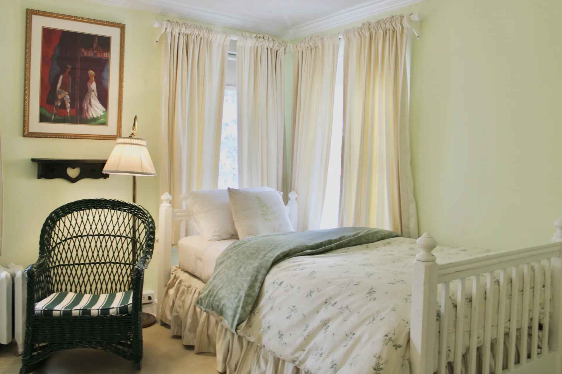 A light and bright room with lush colors of bedding and tall curtains.