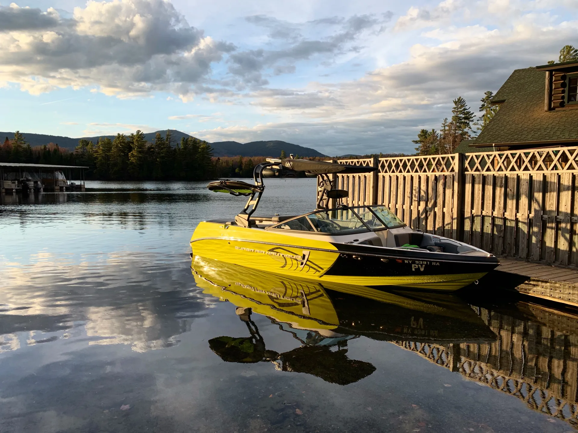 A ski boat sits at the dock at golden sunrise.