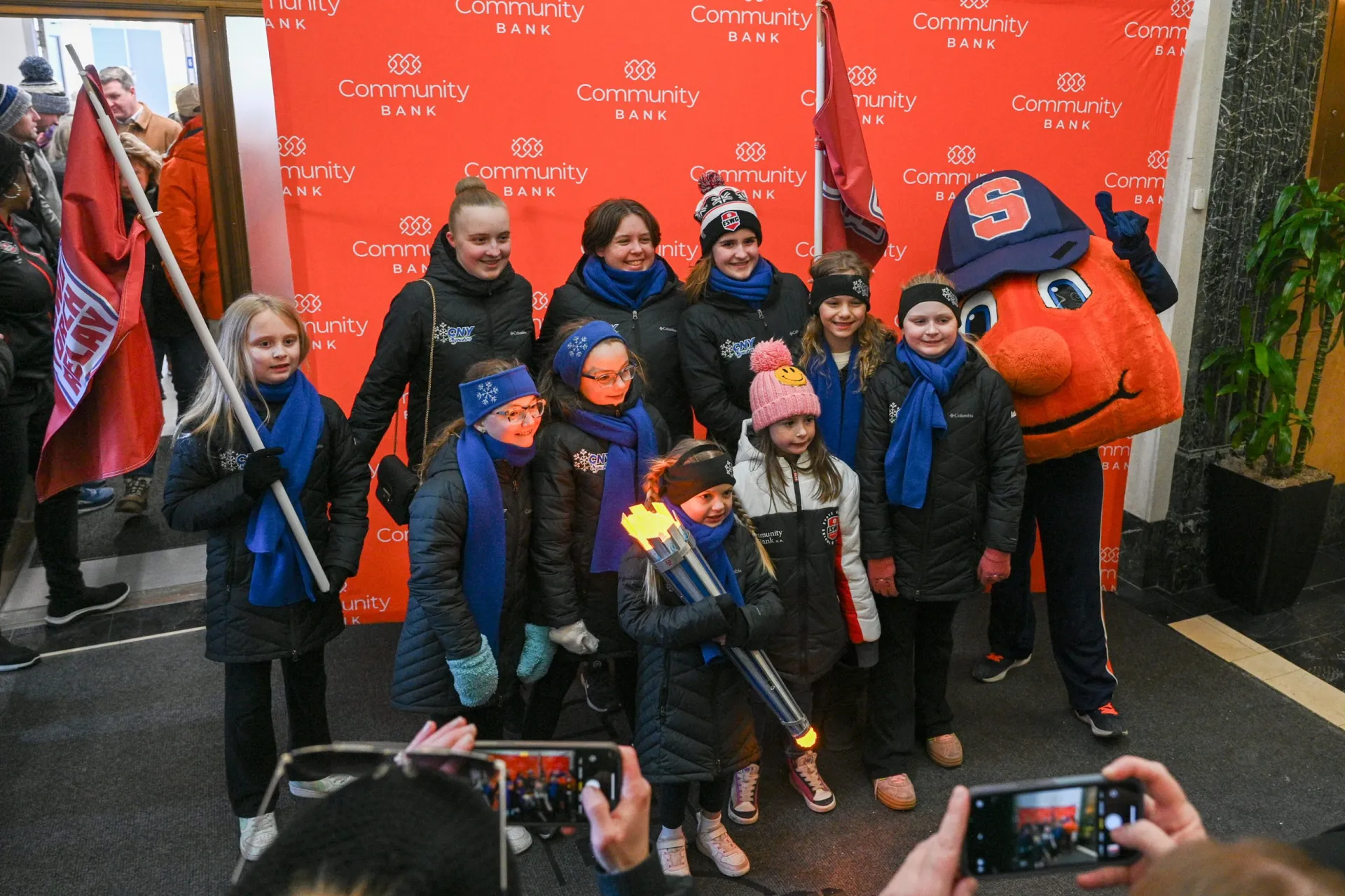 A group of children in winter coats and blue scarves, holding a torch during the Empire State Winter Games Torch Relay.