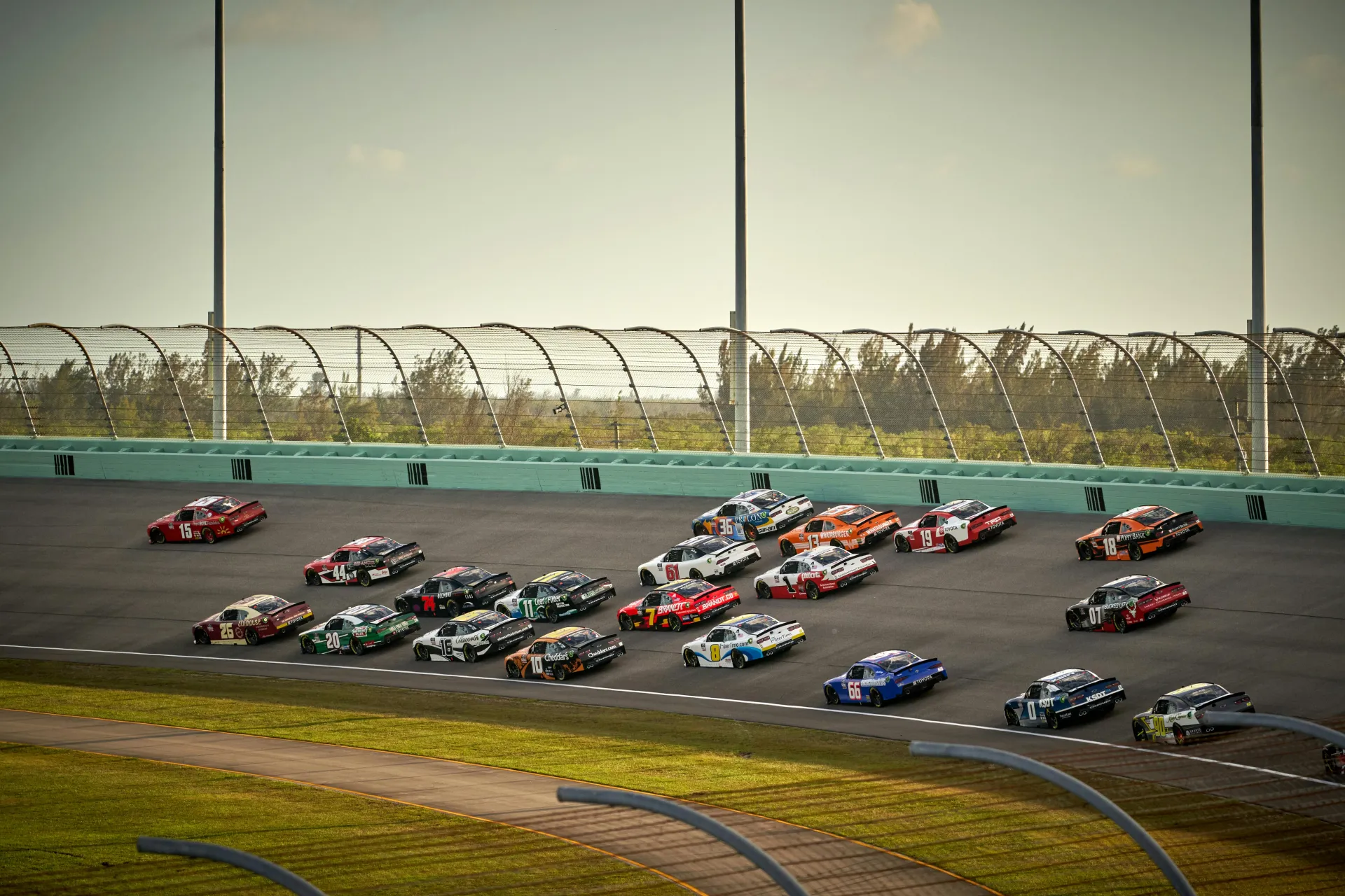 Nascar vehicles race around a paved track