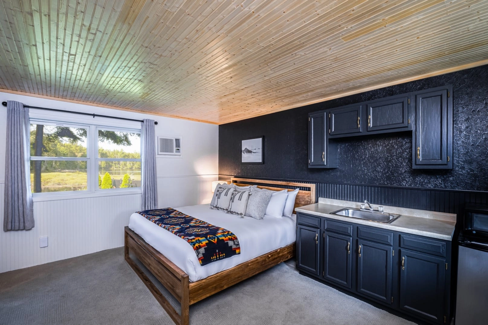 White linens on the large bed with dark blue cabinets in the suite at Placid Bay Hotel.