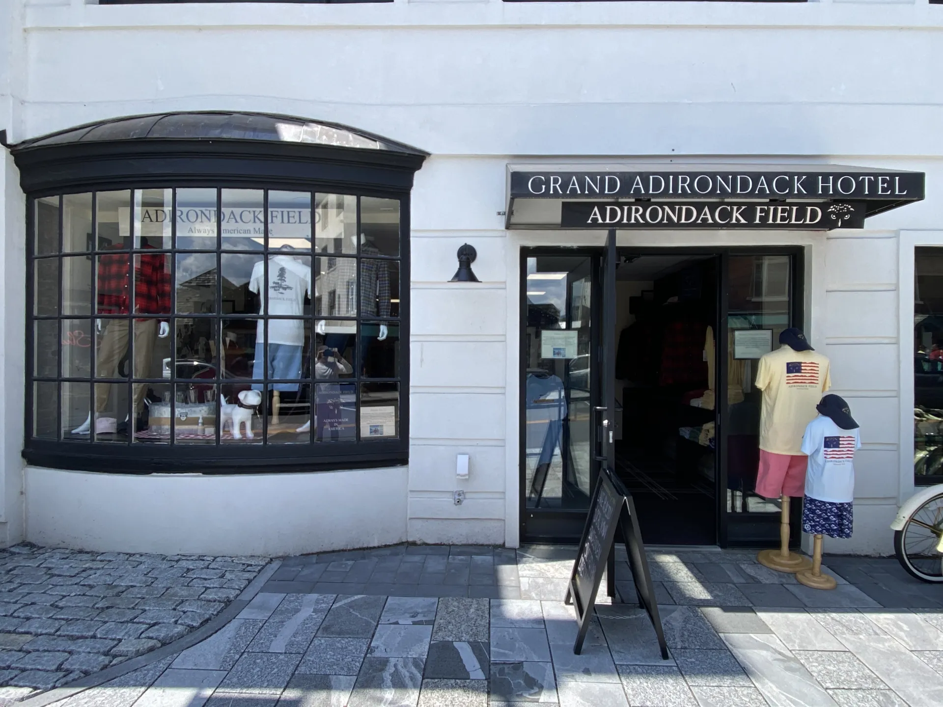 The entry of the white building with black trim and awning for Adirondack Field.