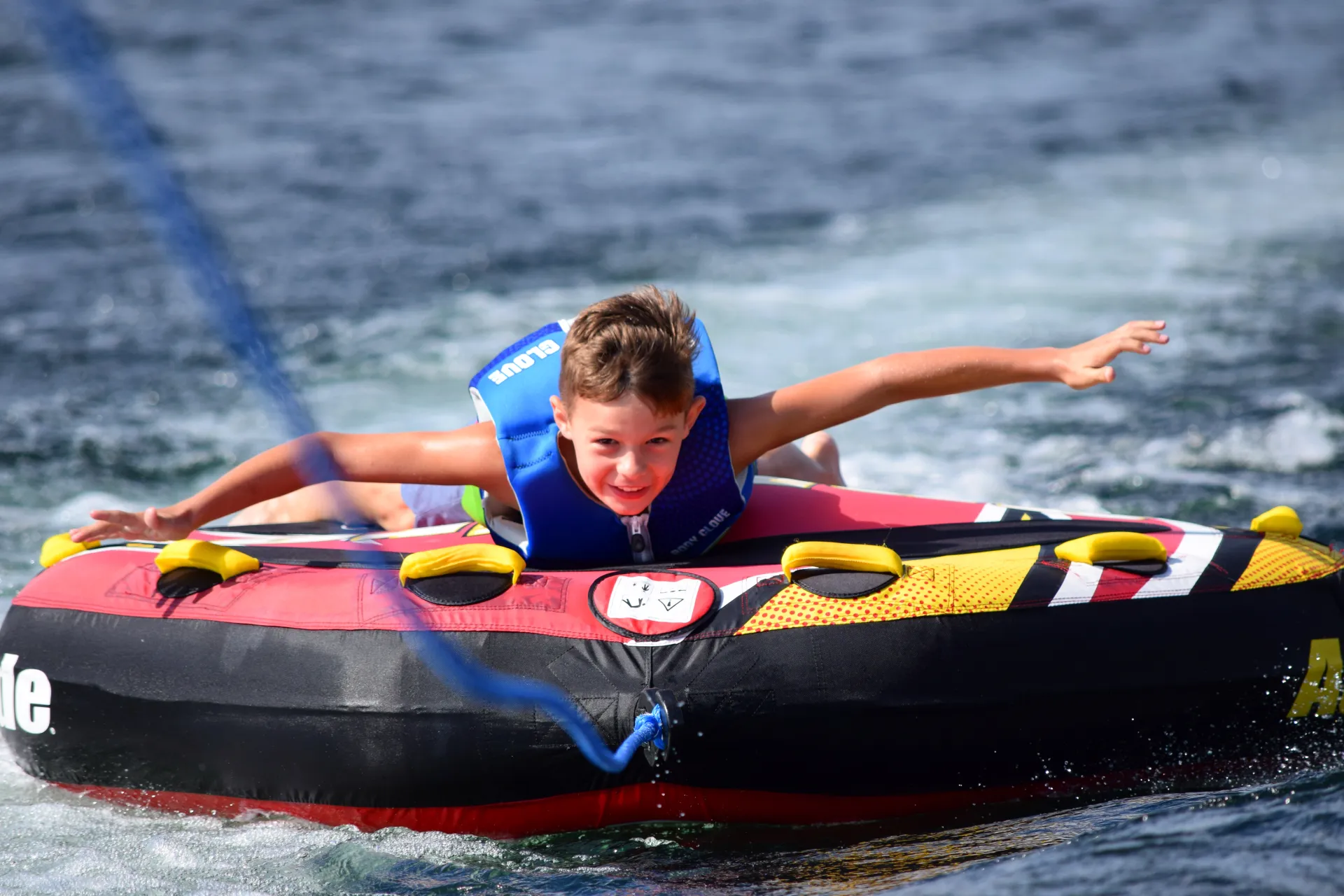 A young boy tubes with out holding the handles.