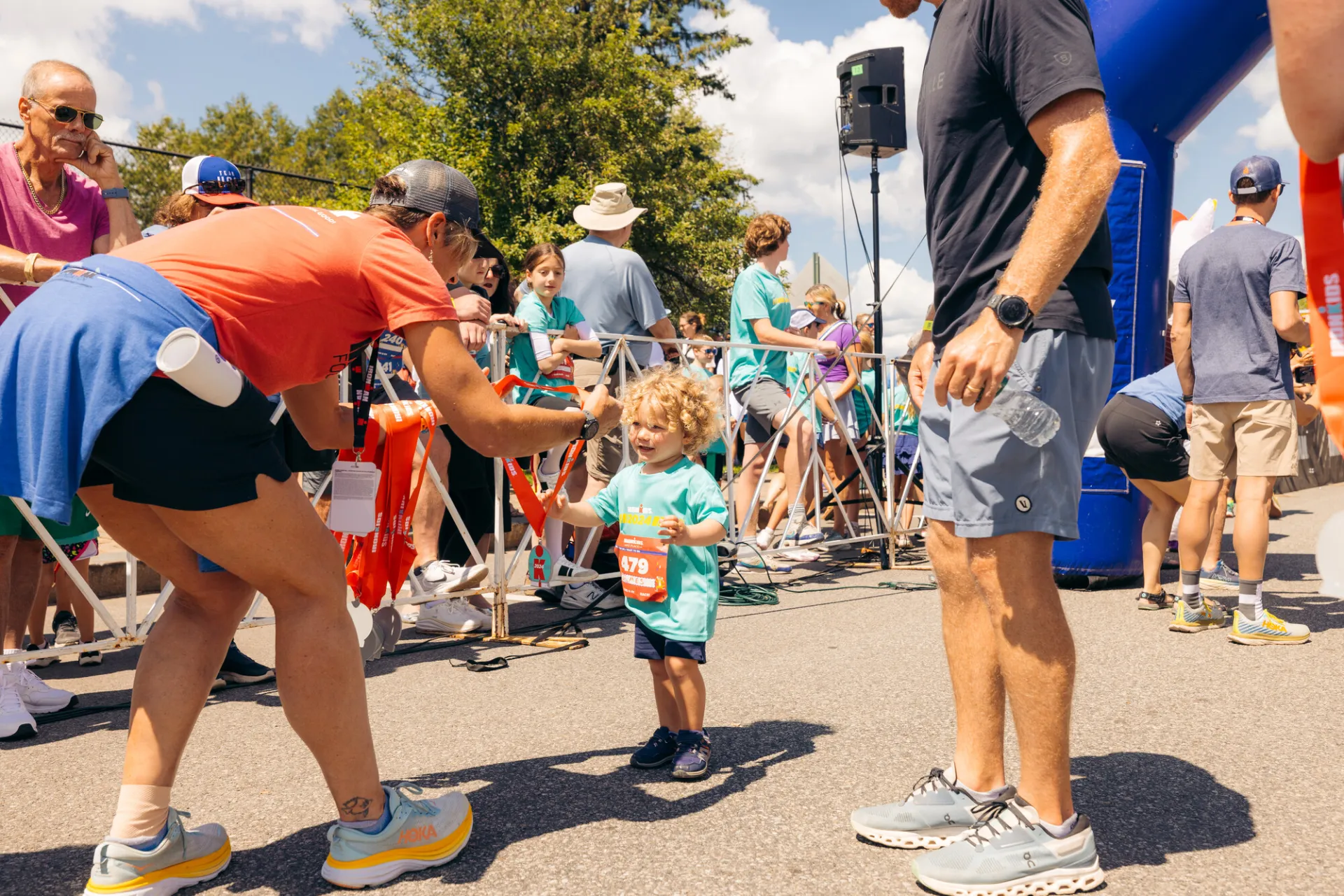 Race worker hands medal to small smiling child at finish line of Lake Placid Ironkids race