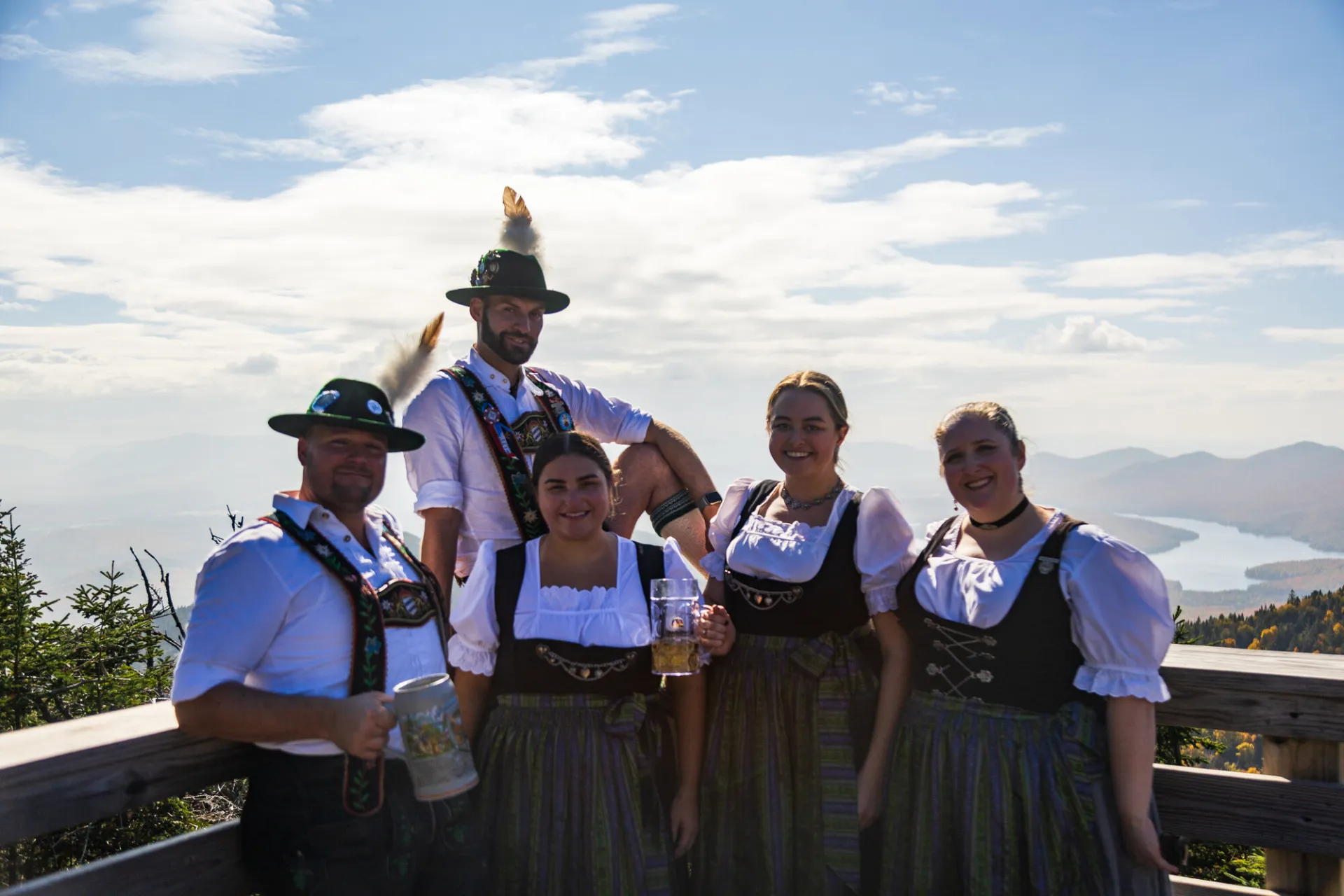 A group of men and women pose for a picture on a deck with german traditional clothing on.