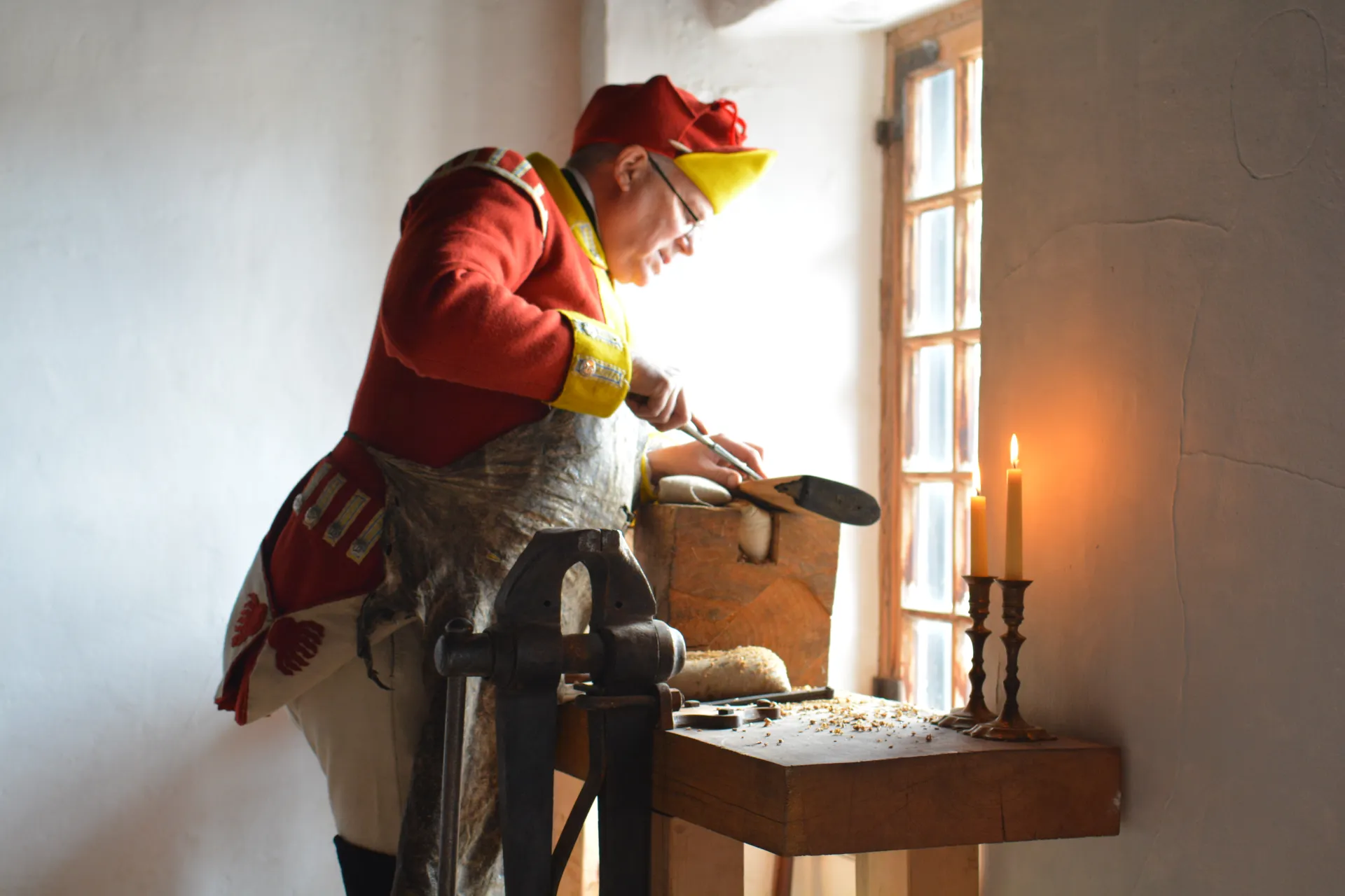 A reenactment performer carves into the stock of his musket.