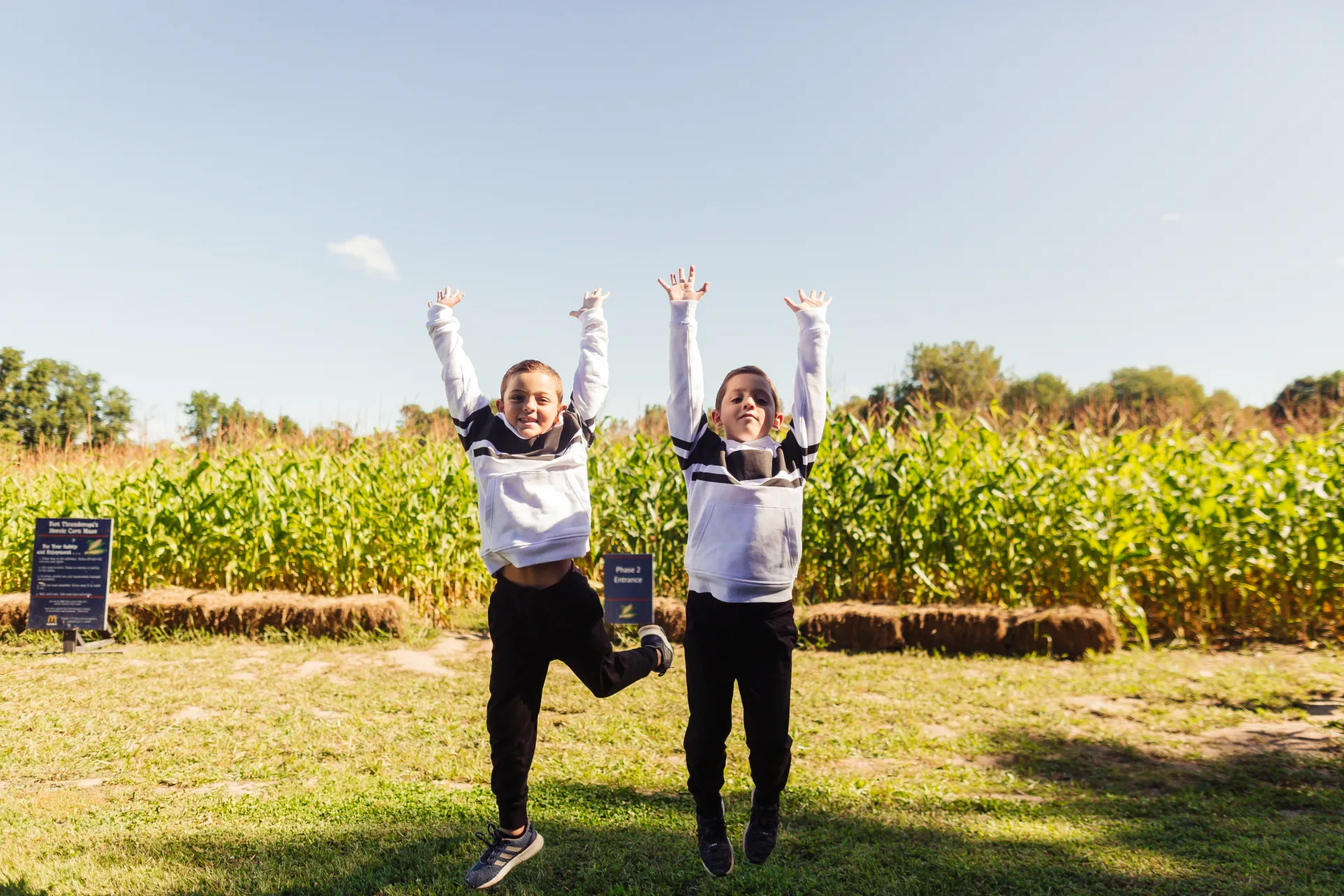 Two boys throw their hands up in excitement after completing the corn maze