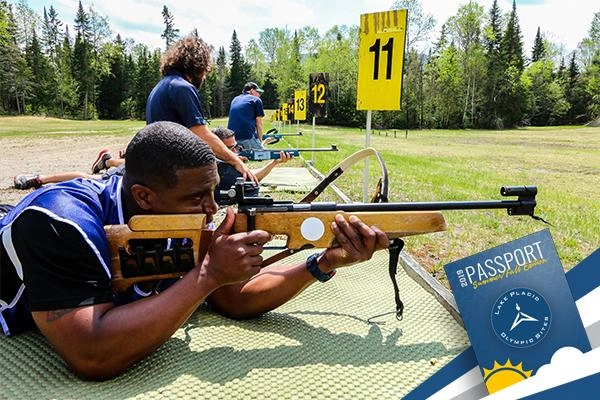 A man takes aim with a biathlon rifle on a sunny summer day.