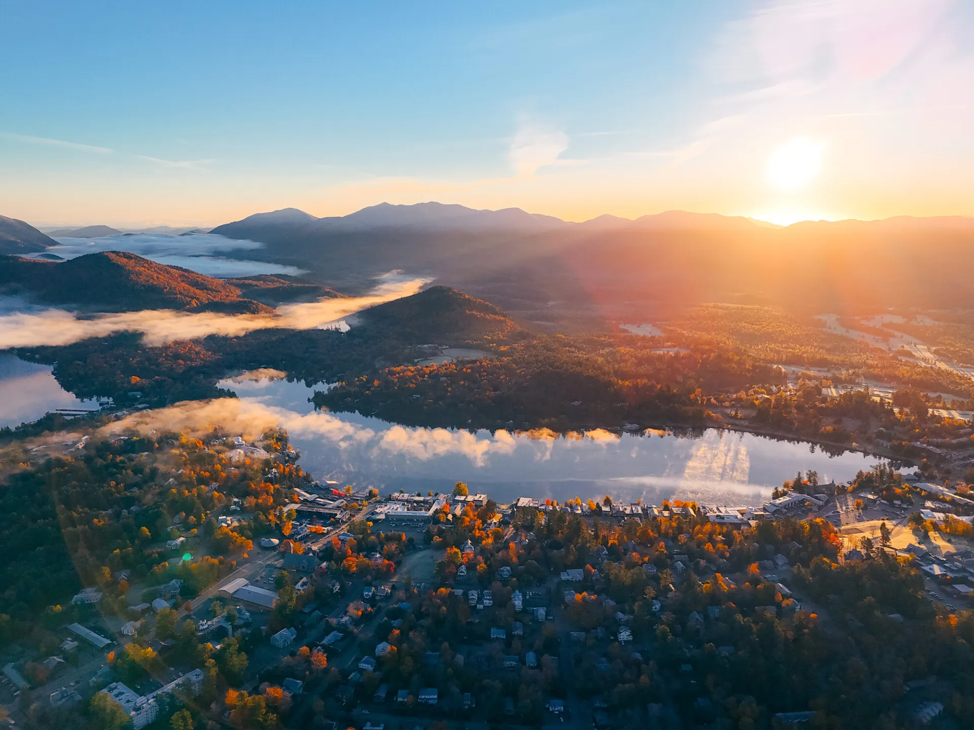 An aerial view of the mountain town of Lake Placid at sunrise on a fall day.