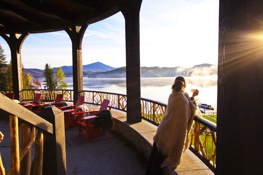 A woman sips coffee on a grand lodge terrace. 