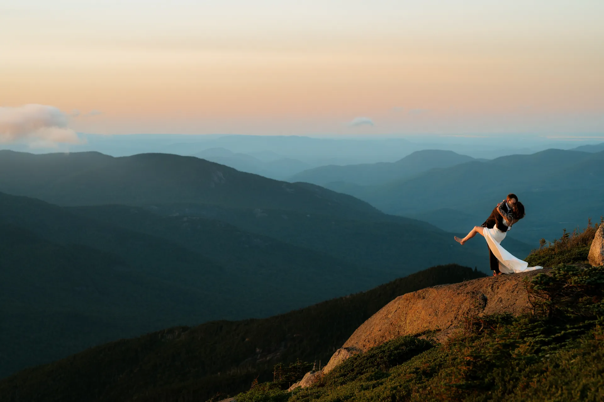 A dip and a kiss of bride and groom on top of a mountain