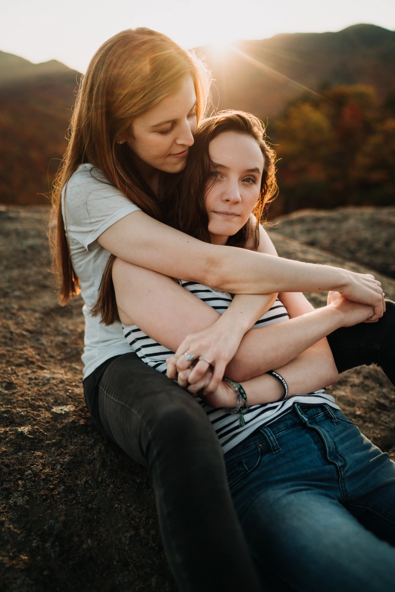 2 woman embracing on top of a mountain