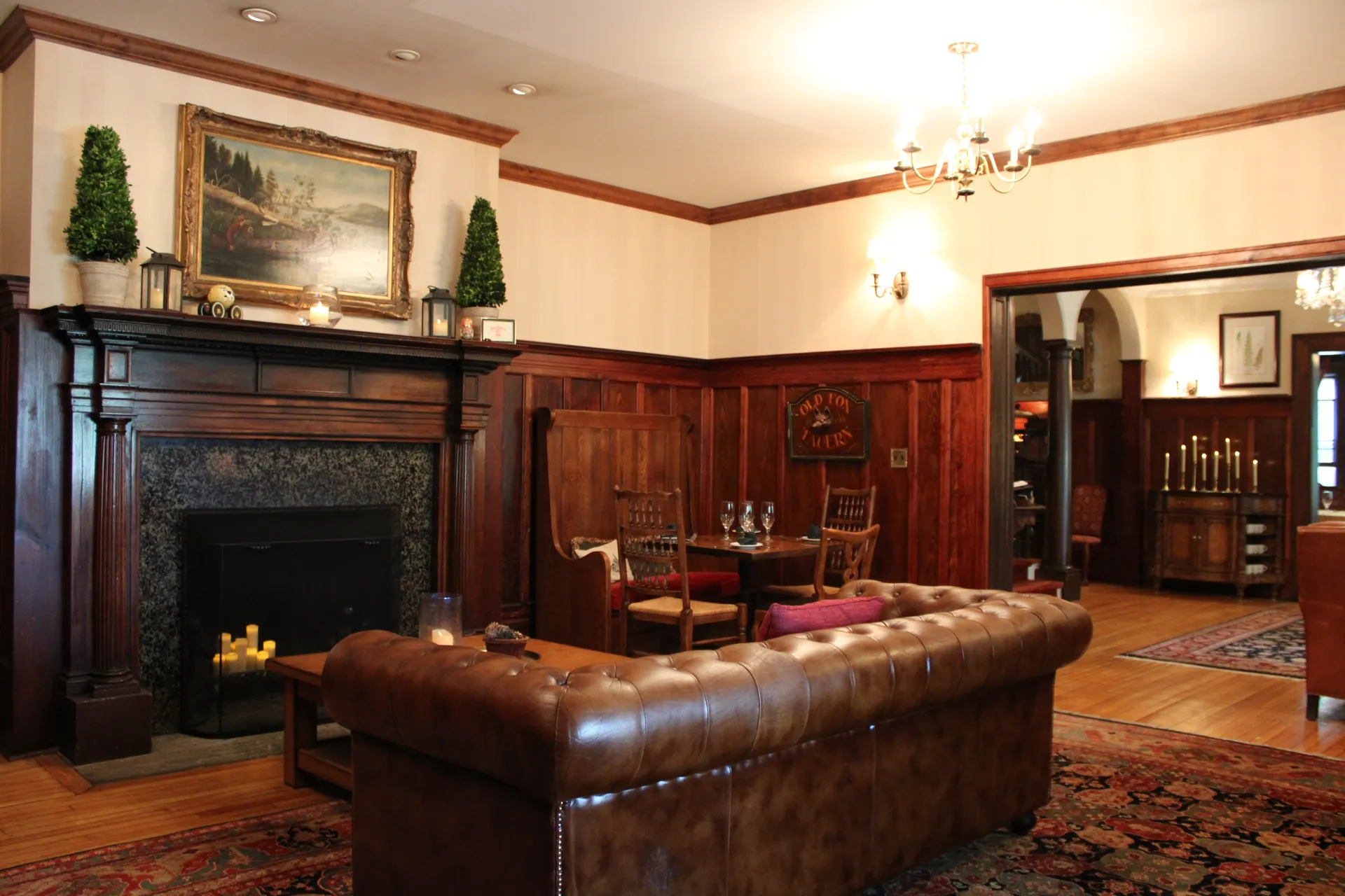 A dark, tufted leather couch with dark trim and wainscoting by a fireplace.