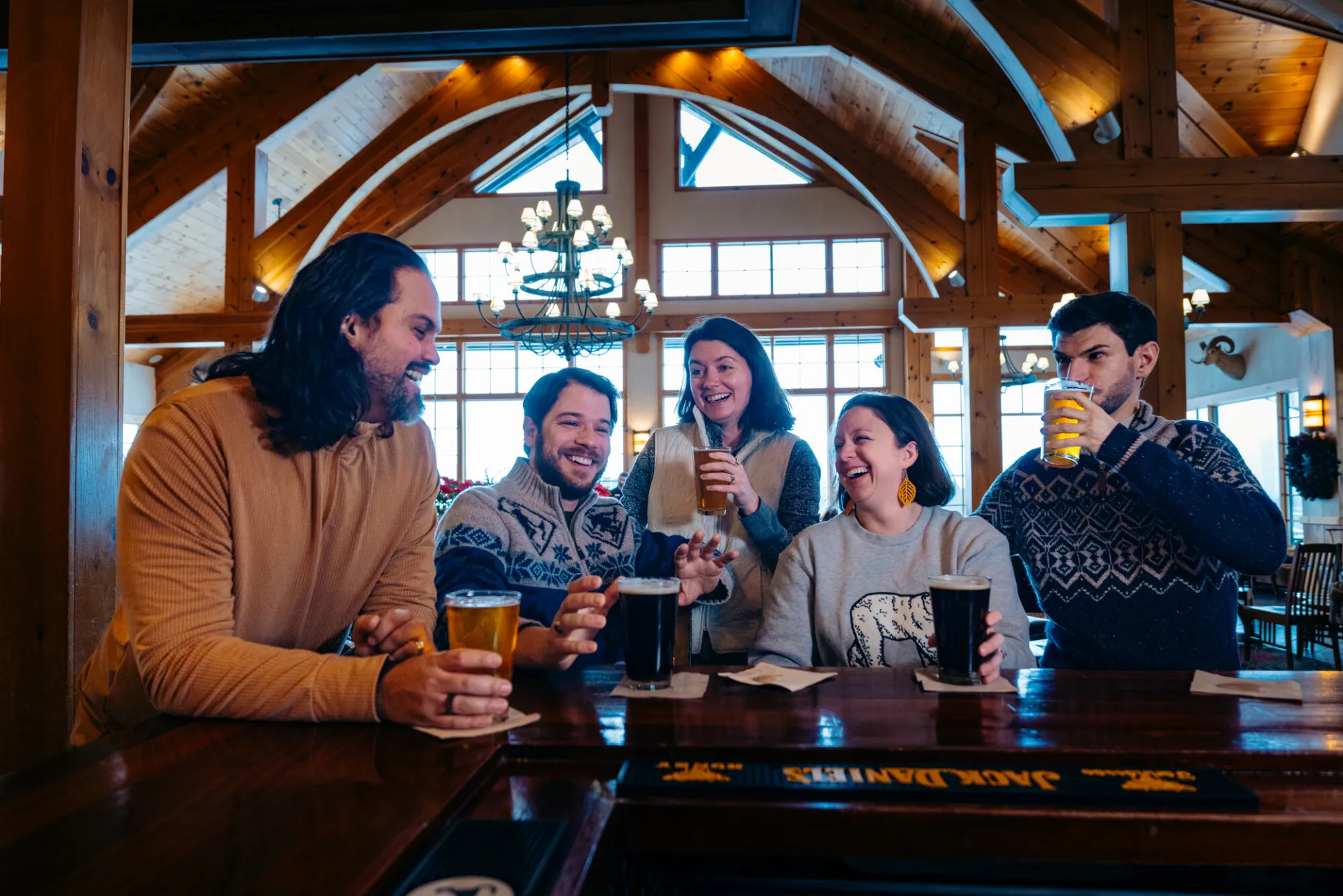 A group of friends enjoy drinks at a bar in a grand lodge.