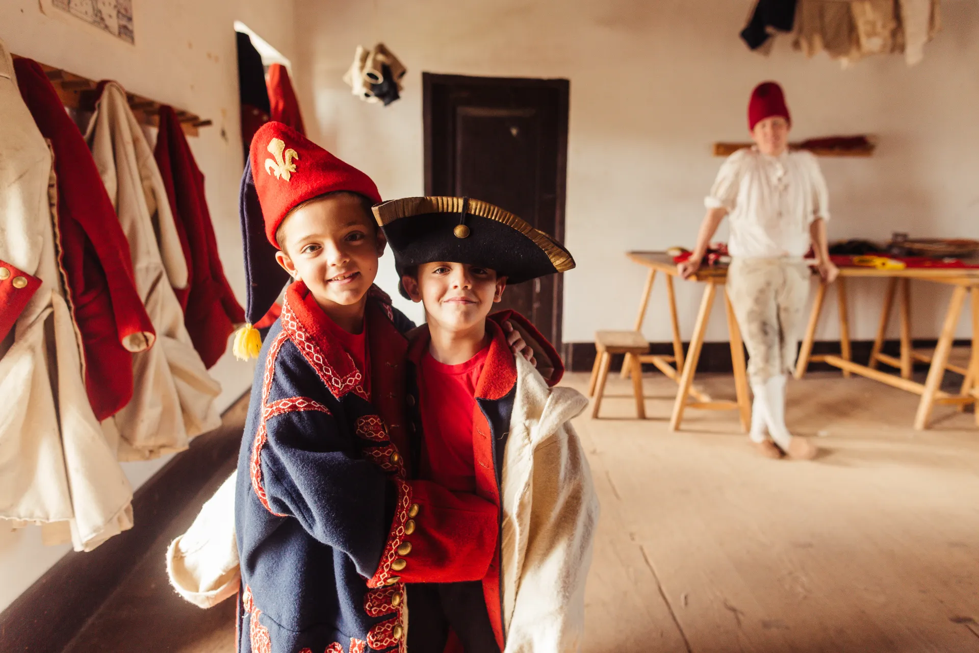 Two young kids show off the period outfits they put together while a reenactment actor smiles in the background