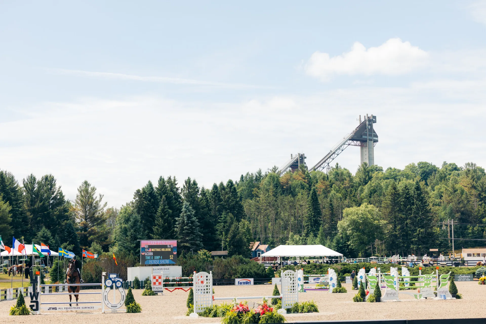 View of Lake Placid Horse Show Grounds during annual horse show with courses set up and ski jumps in the background