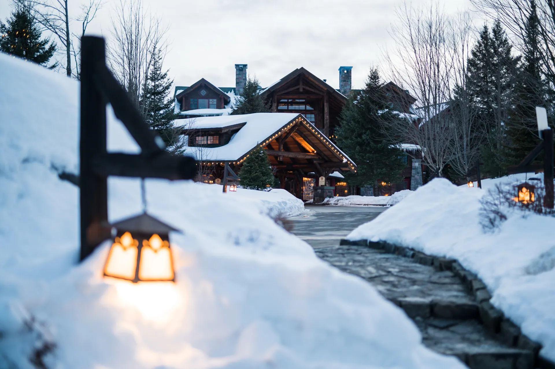A rustic hotel lodge is tucked amidst snowy lawns.