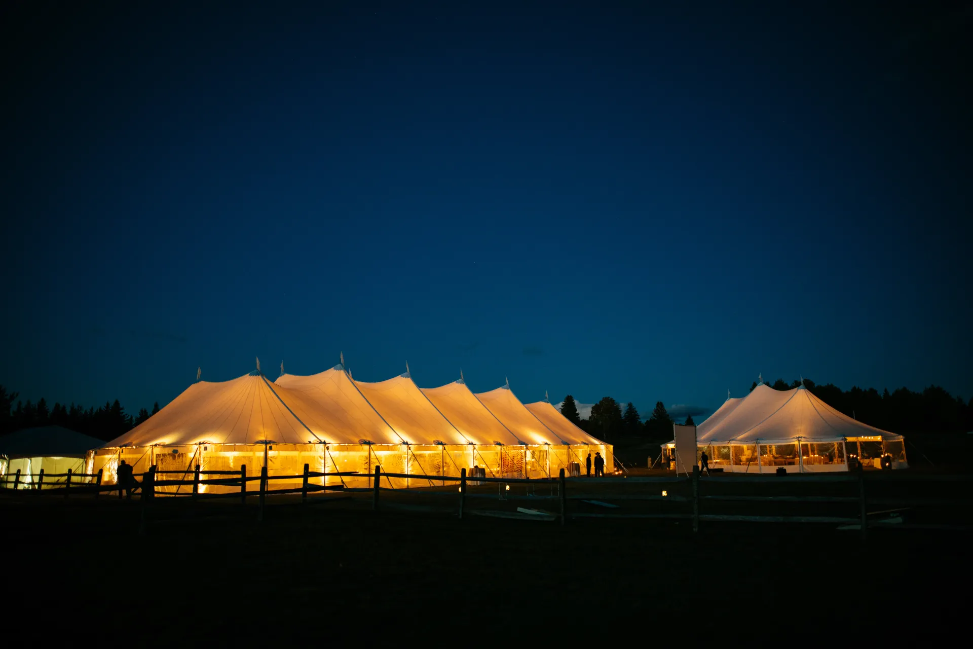 Illuminated tents with a golden glow against the deep blue ski