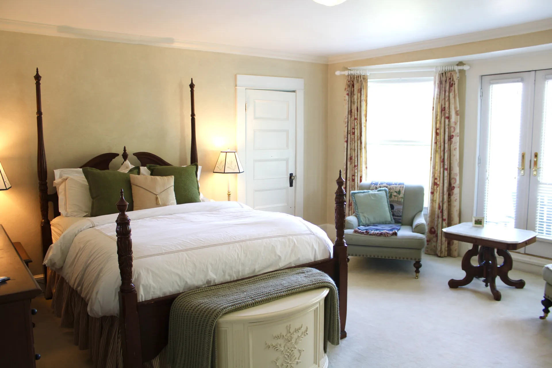 Dark four poster bed with large windows and arm chair.