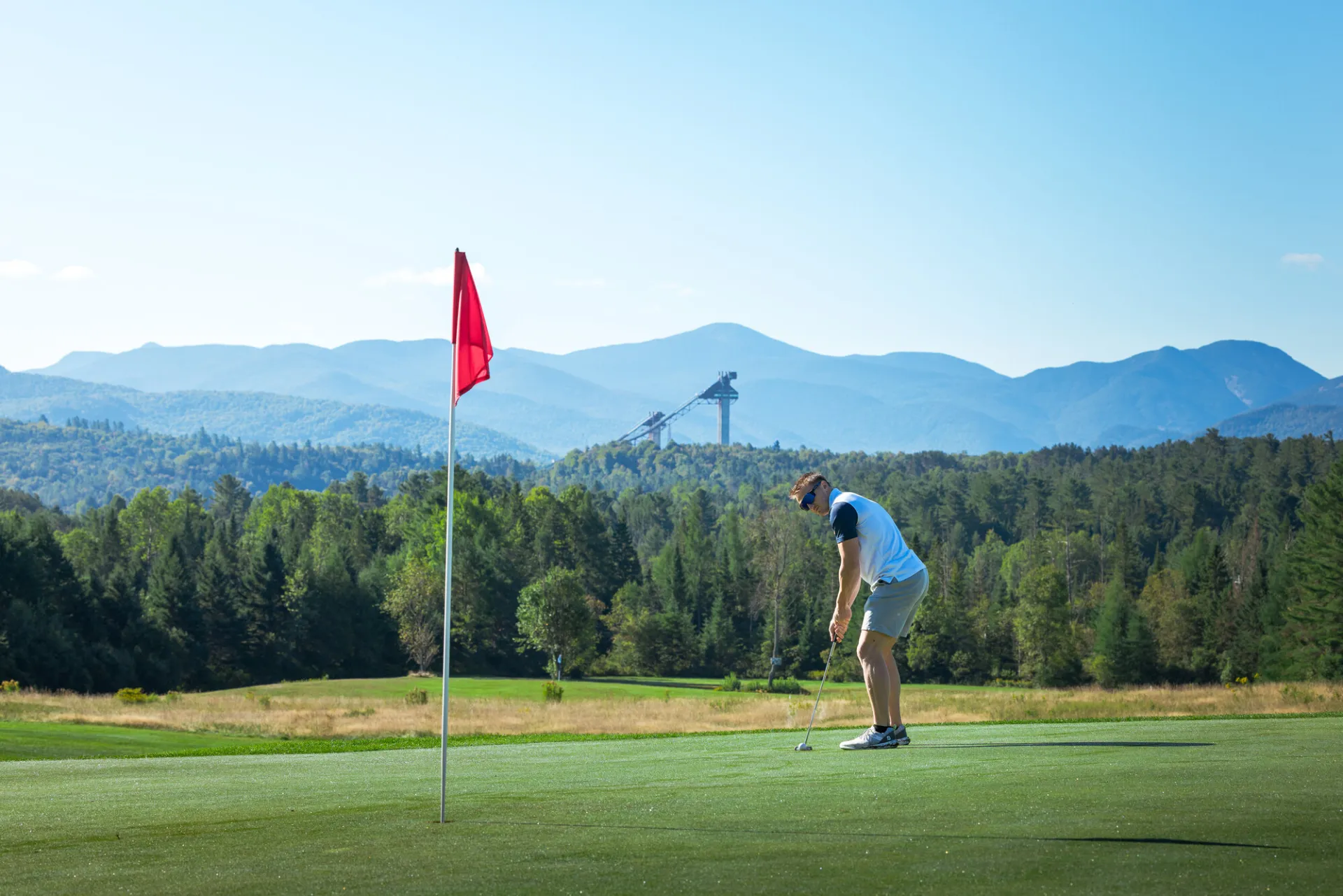 A man hits a golf ball into a hole on a golf course.