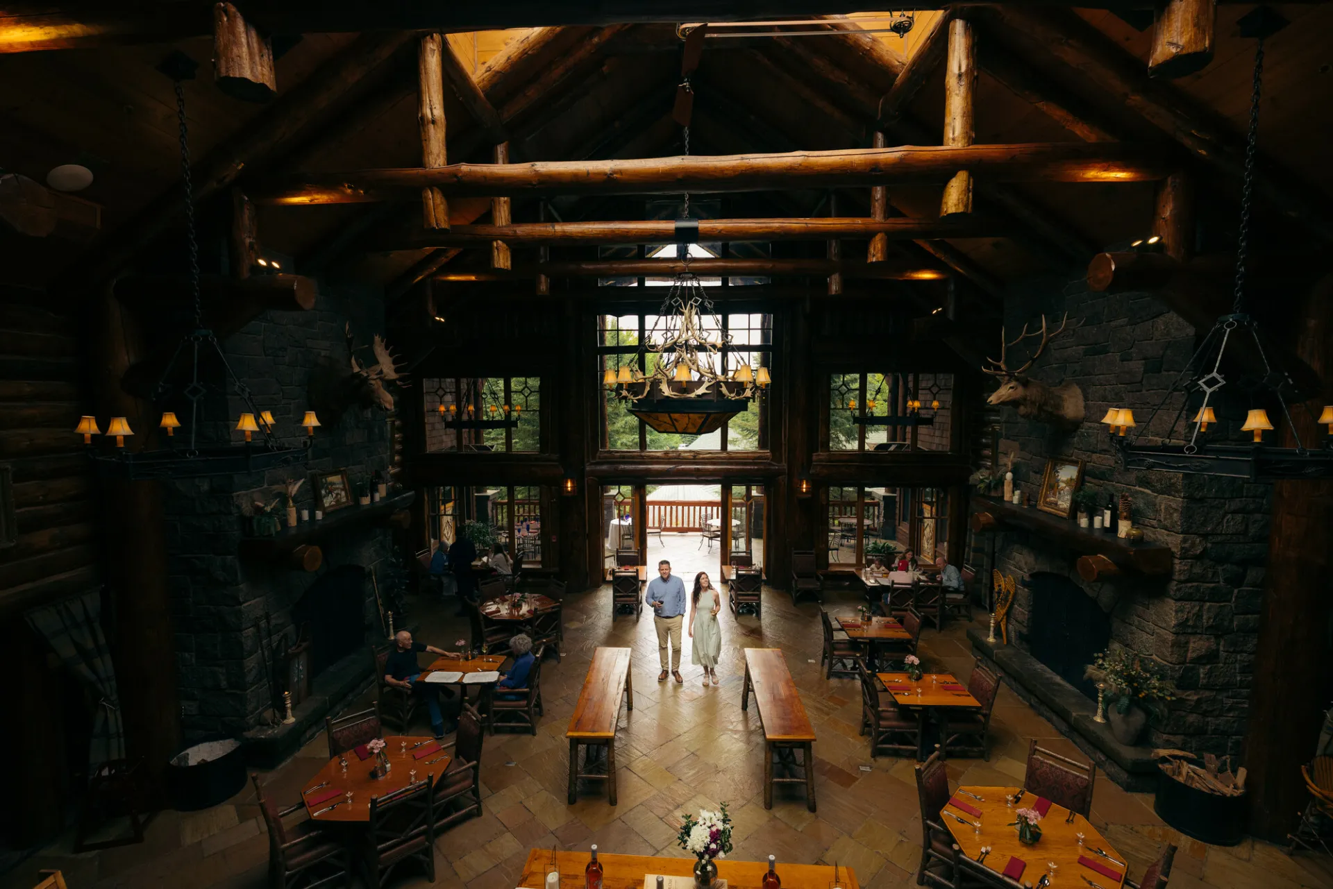 A man and woman walk into a luxury lodge dining room. 