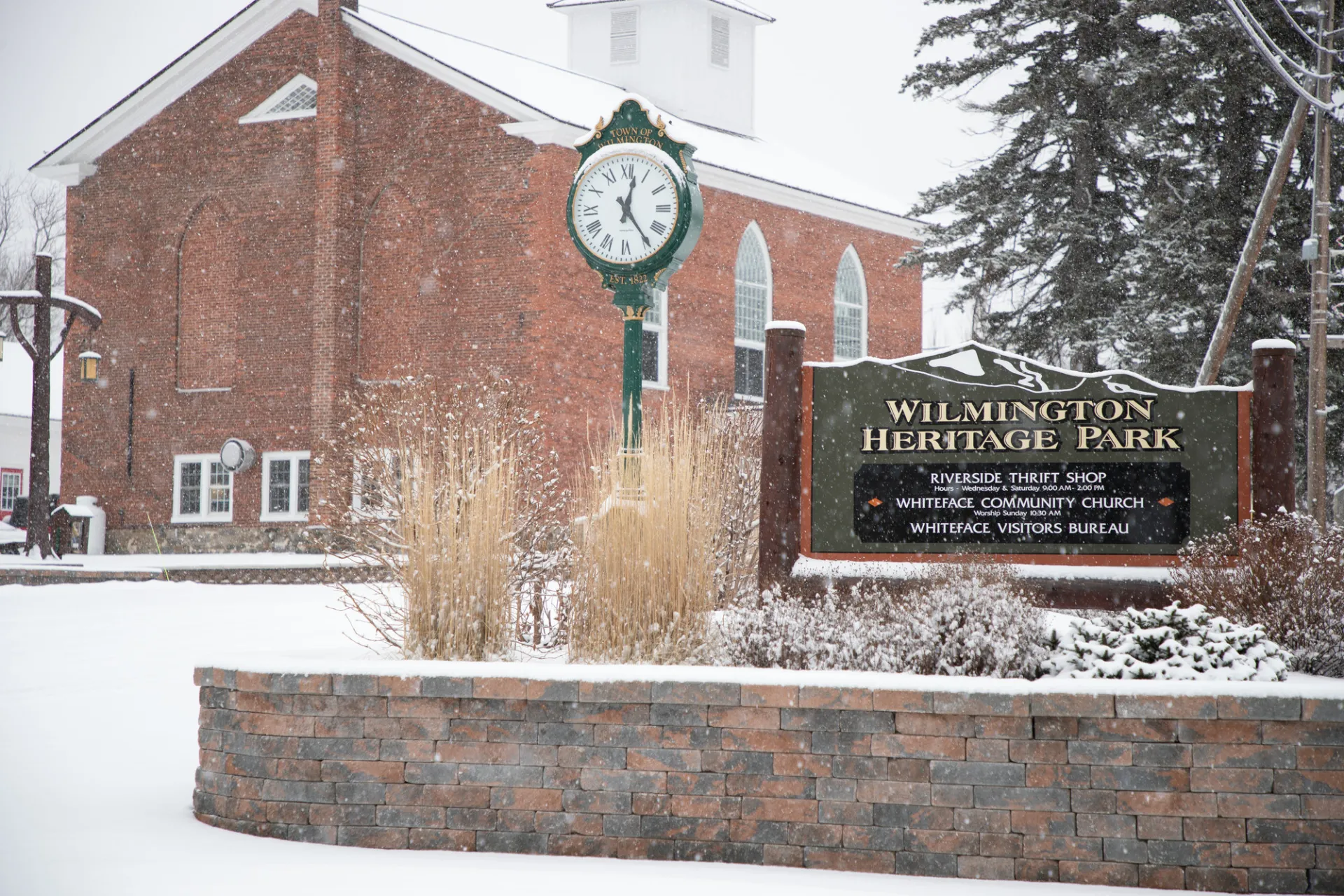 A church in the snow with a Wilmington Heritage Park sign in front of it. 