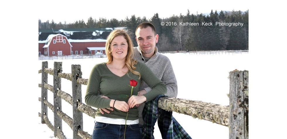 A man and woman stand by a fence in winter.