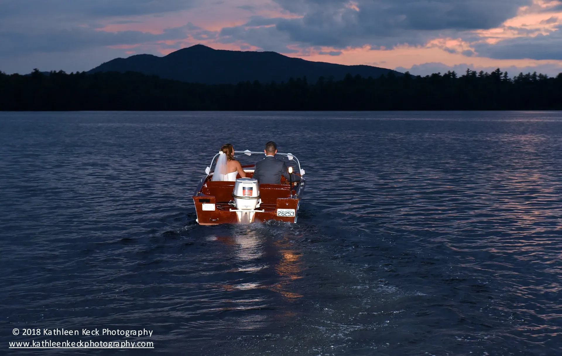 Bride and groom sail into the sunset on a wooden chris craft boat.