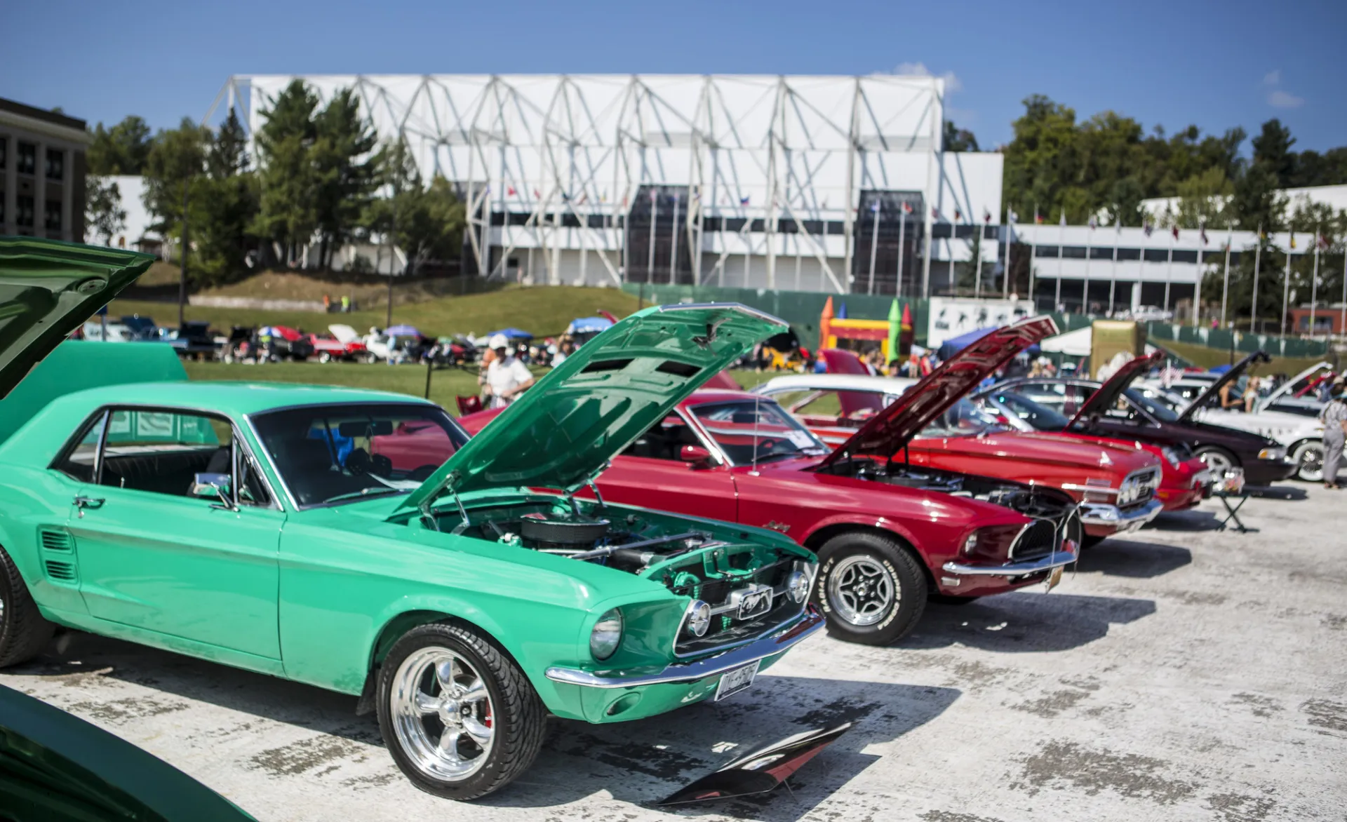 Colorful classic cars parked in a row with their hoods up on Olympic Oval for car show