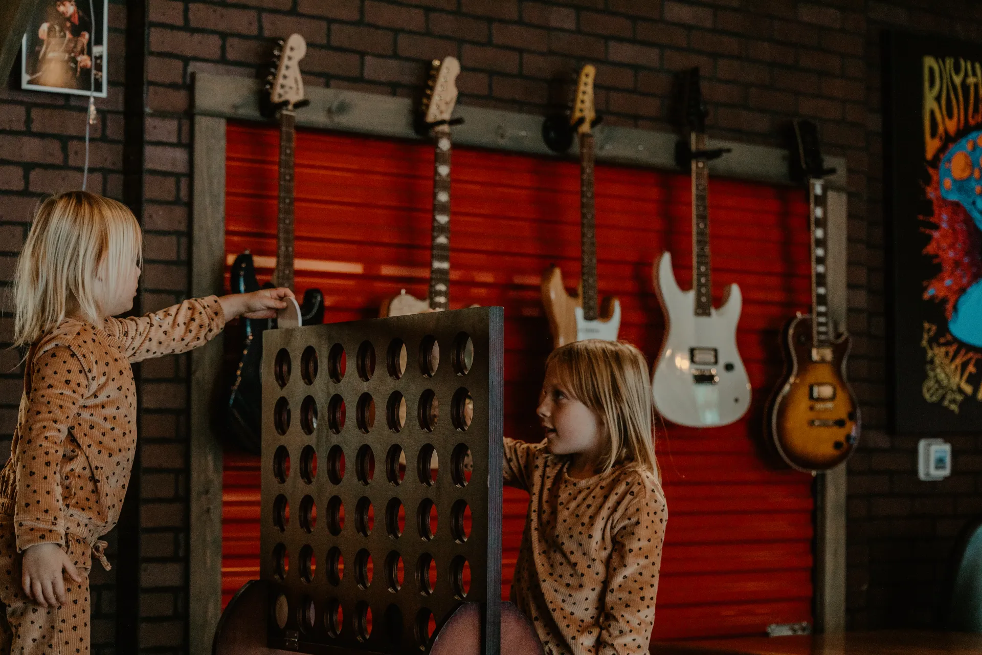Two girls play giant connect four in front of a wall full of guitars.  Photo Credit to A. Kelly.
