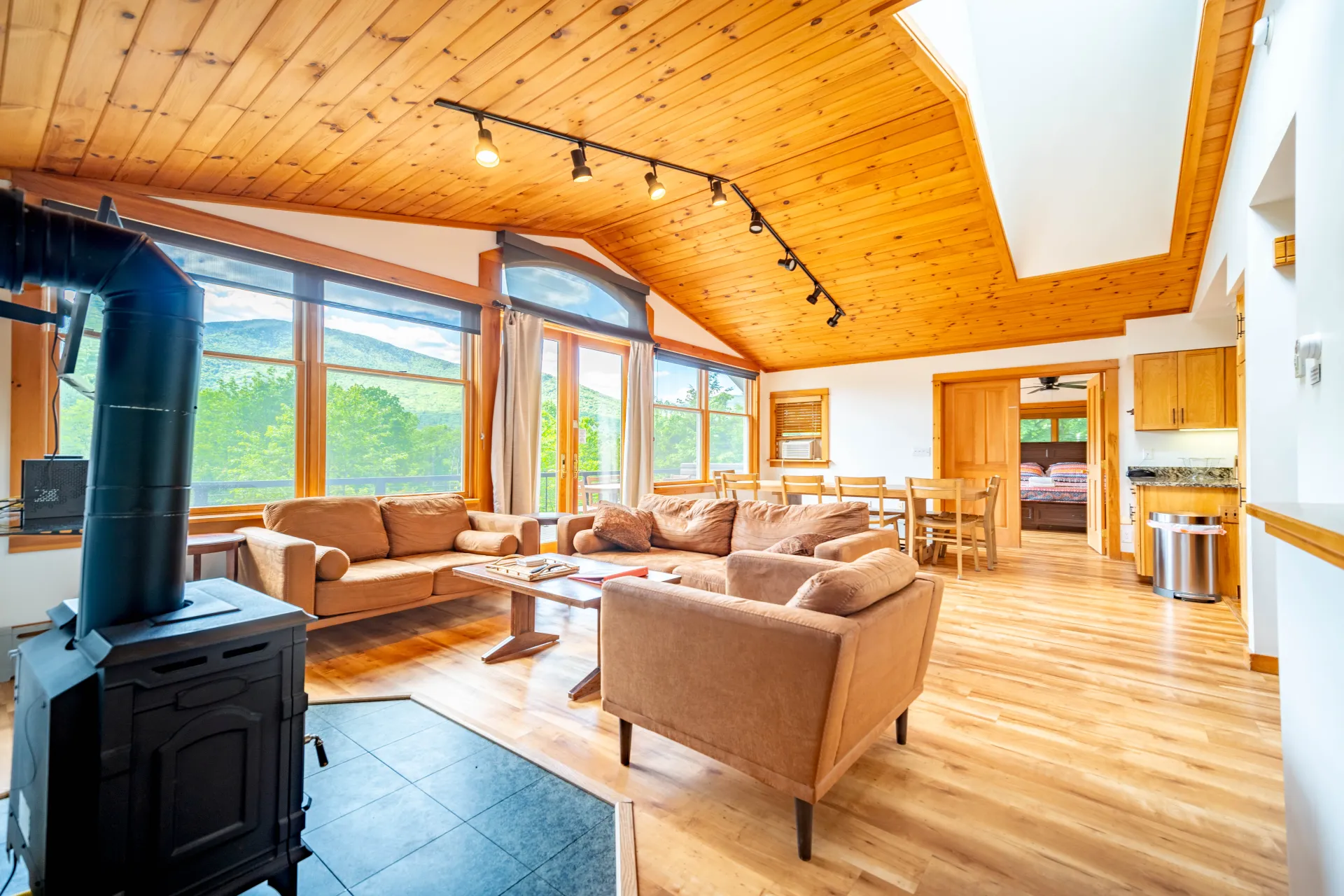 Interior Great Room with comfy couches, a wood stove and knotty pine paneling throughout