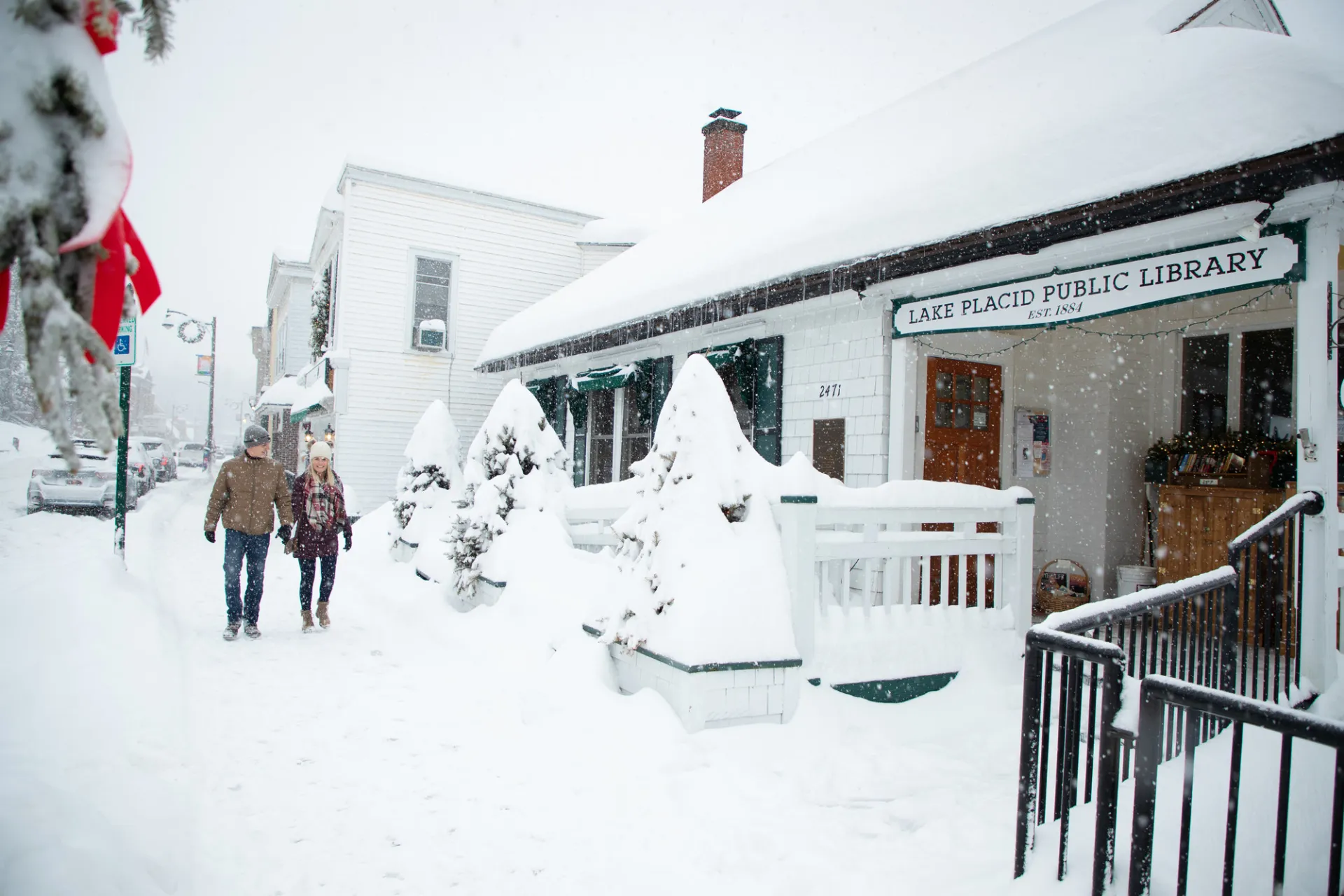 Two people walking down Main Street in Lake Placid on a snowy winter day.