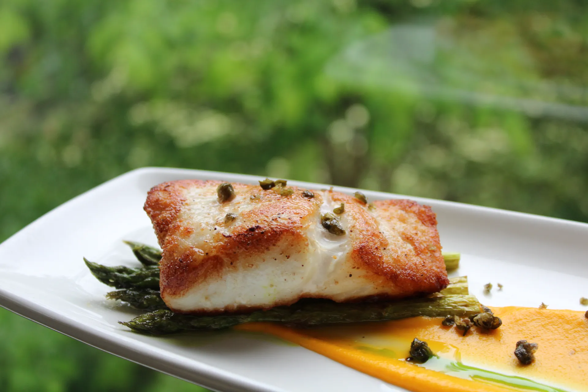 Grilled salmon with capers over asparagus.