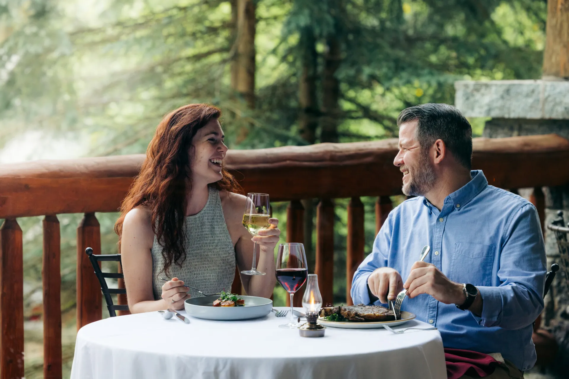 A man and woman share a dinner at a white tablecloth restaurant in a lodge. 