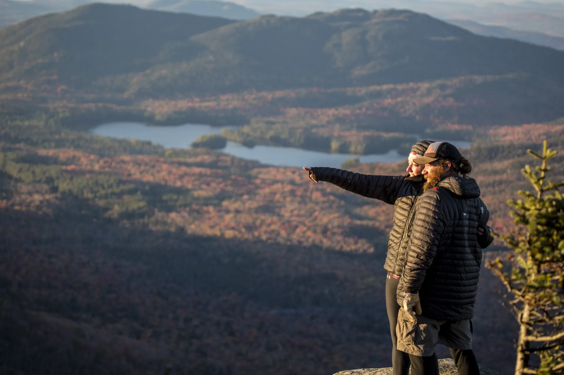 Two people enjoying a tall fall summit view