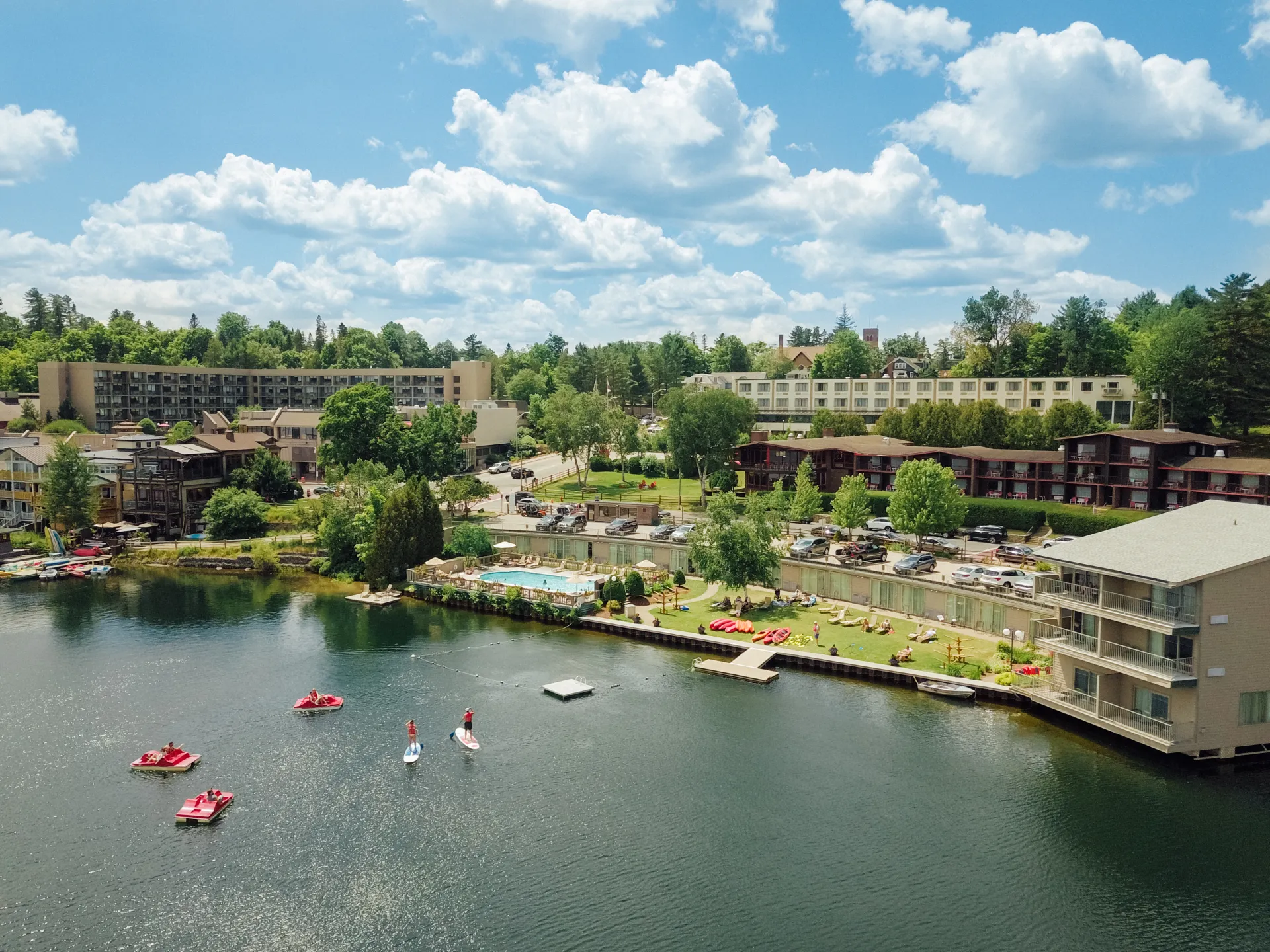 Aerial image of High Peaks Resort from over Mirror Lake in summer. Boats on the water