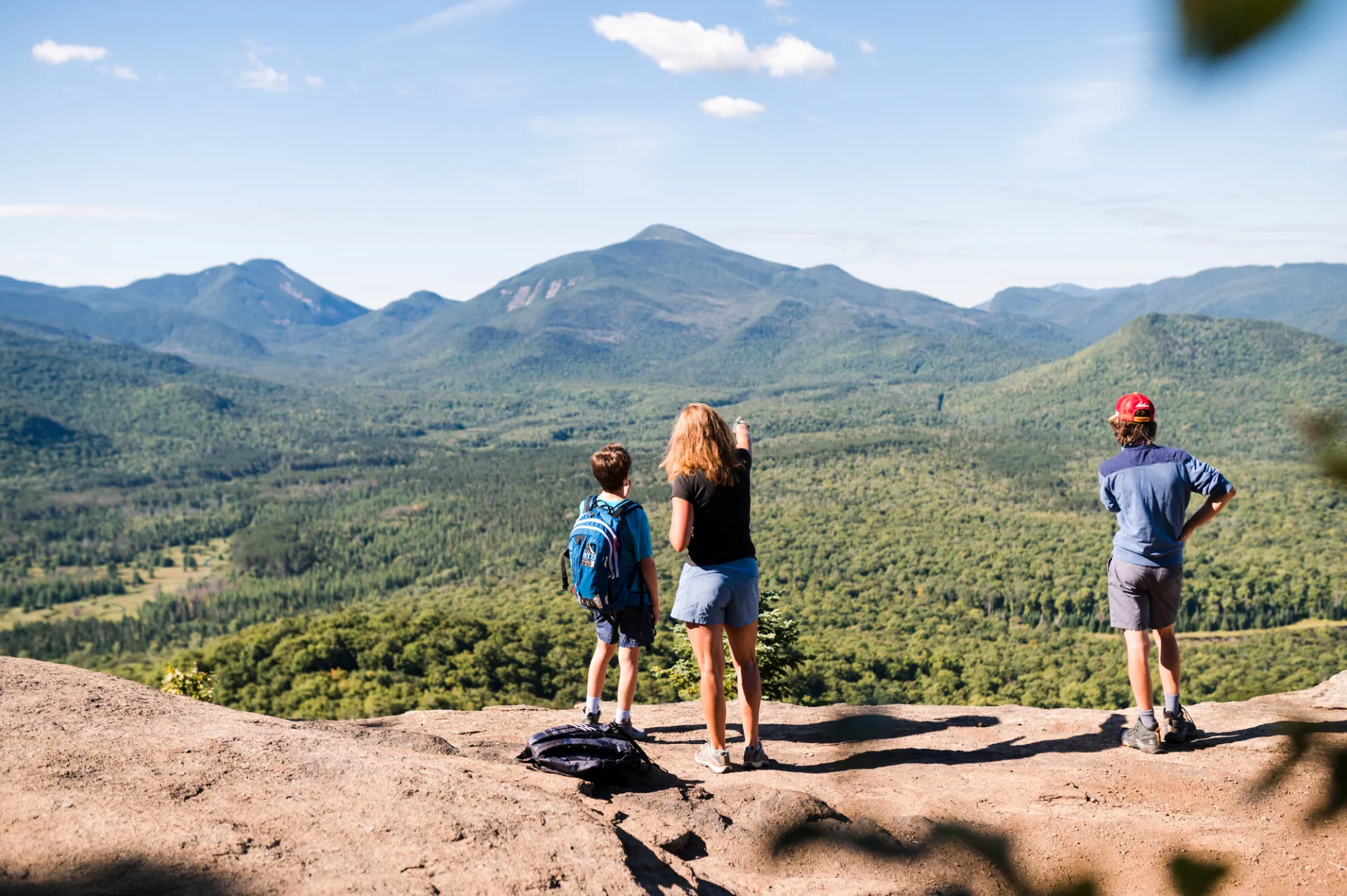 A family looks out to mountains on a summit. 