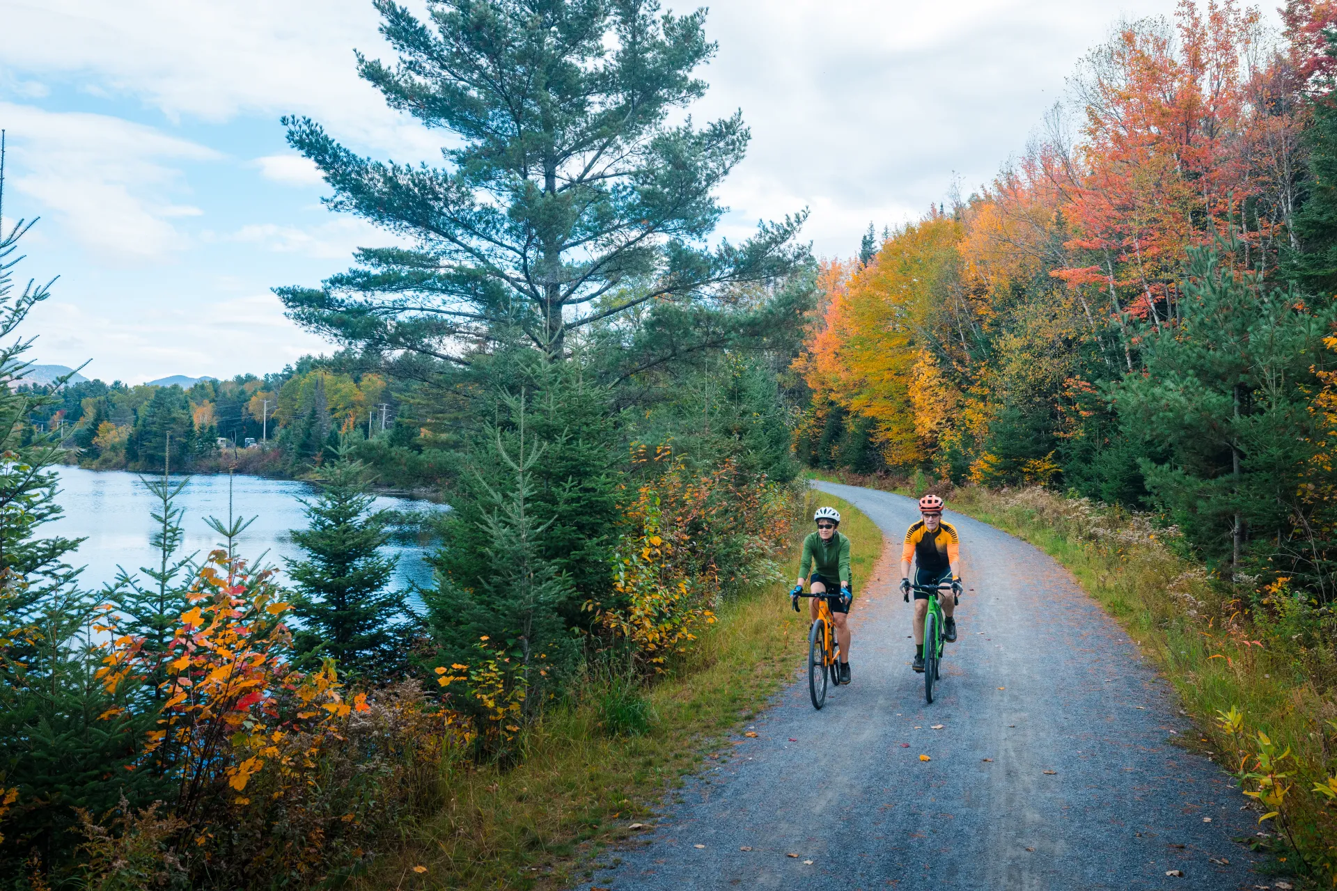 Two people ride their bikes on a fall trail.