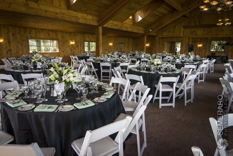 Many round tables set with white chairs and florals, ready for the reception.