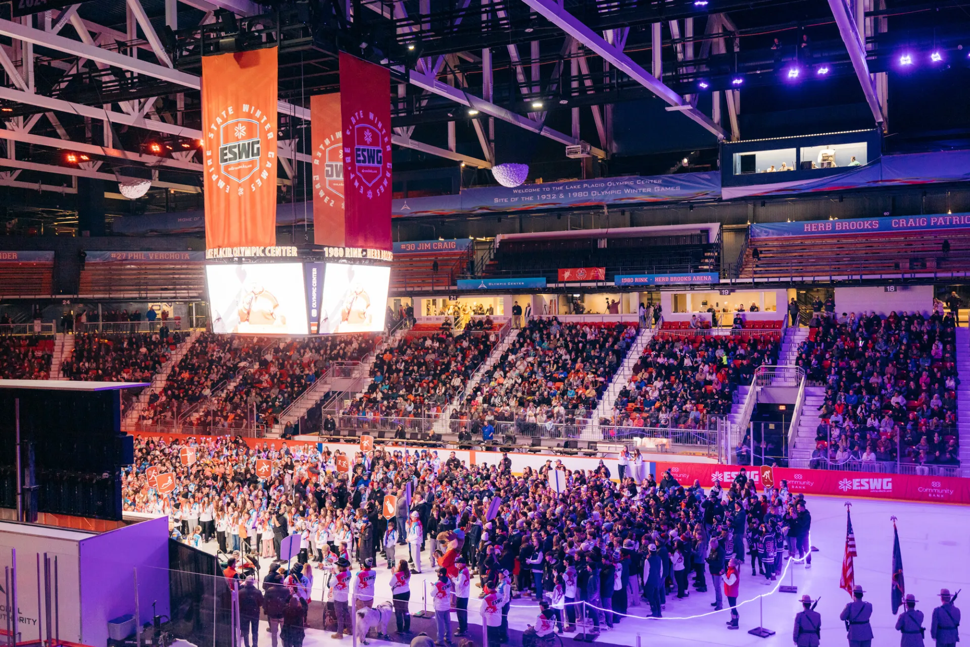 A wide-angle, high angle shot of a crowded indoor ice arena during the opening ceremony of the 2025 Empire State Winter Games (ESWG)