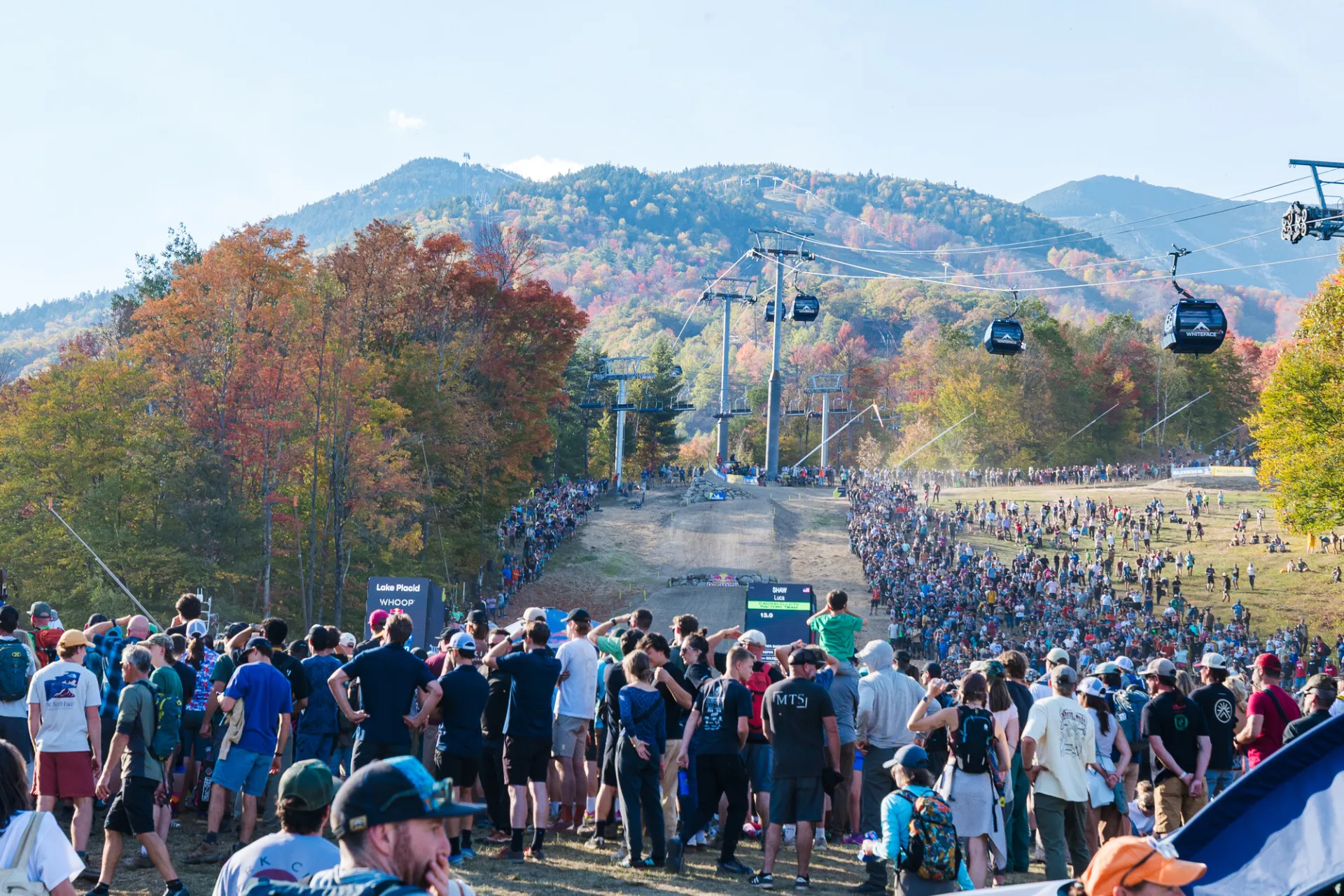 Large crowd gathered at finish line area of 2025 WHOOP UCI MTB Downhill World Cup at Whiteface Mountain with slopes behind