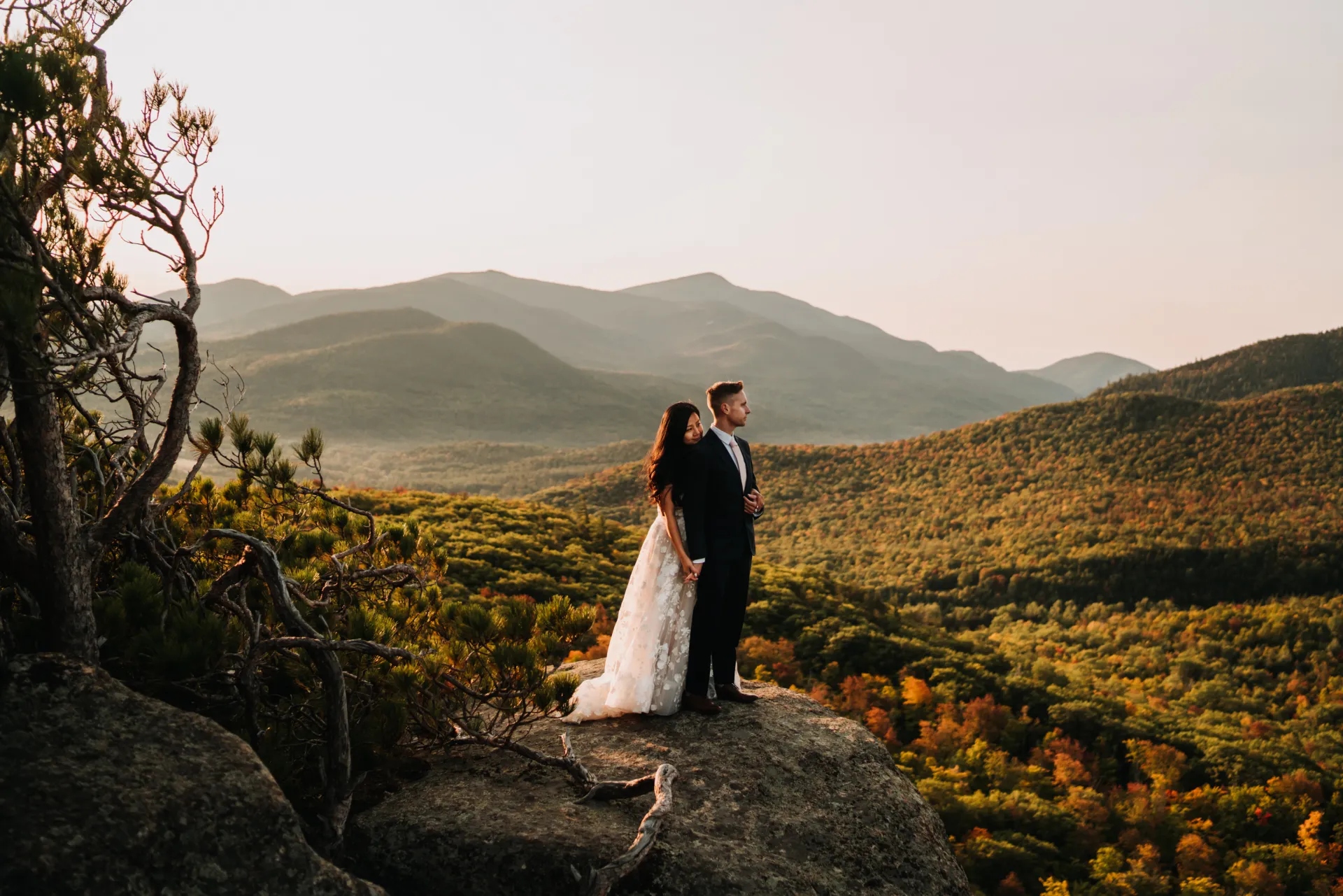a couple looks into the distance on top of a mountain