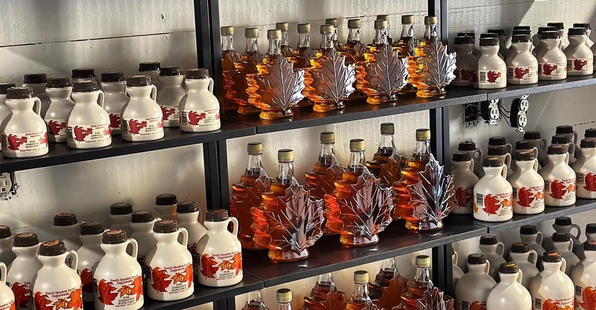 Store shelves stocked with plastic and glass containers of maple syrup