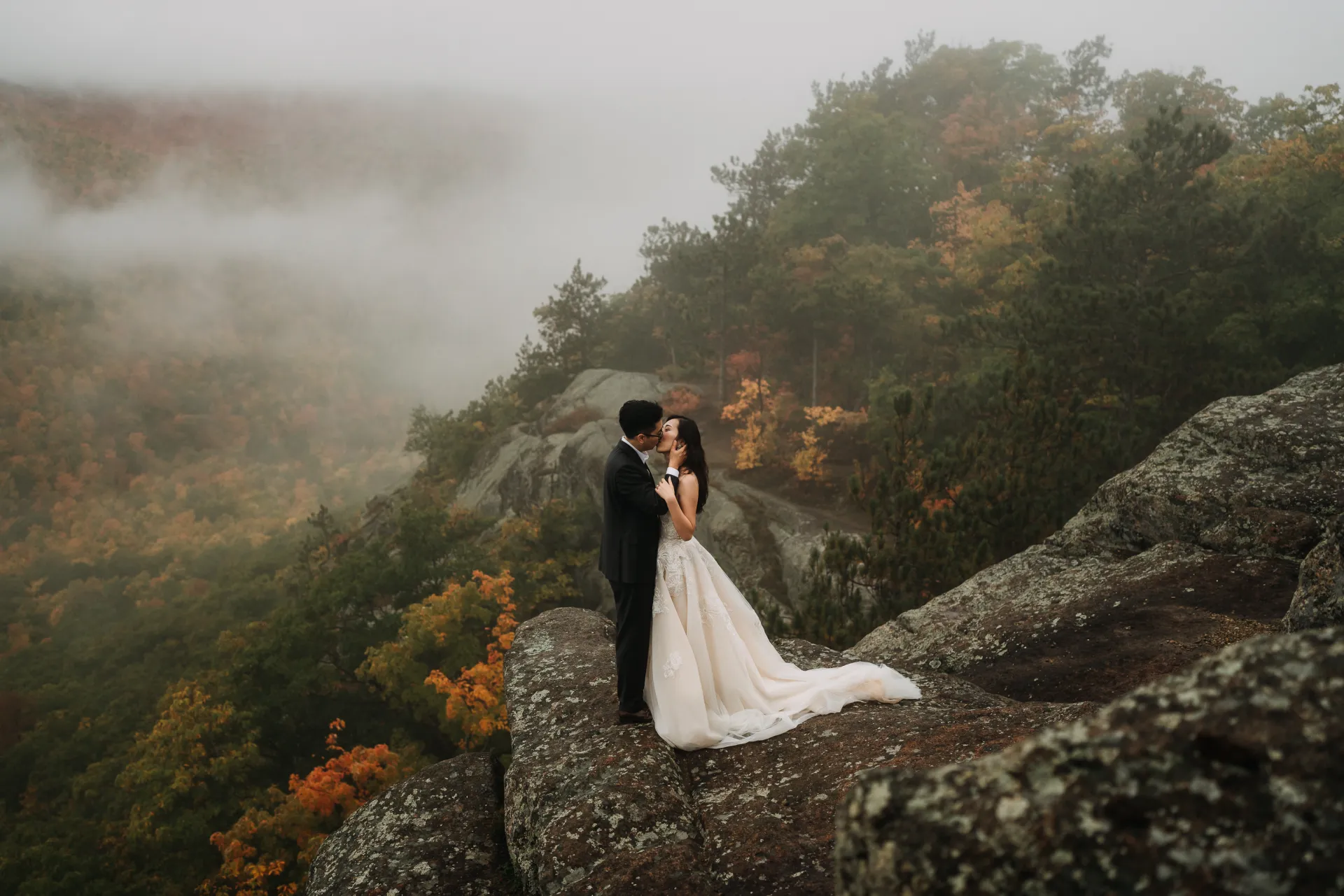 a couple kisses on top of a mountain