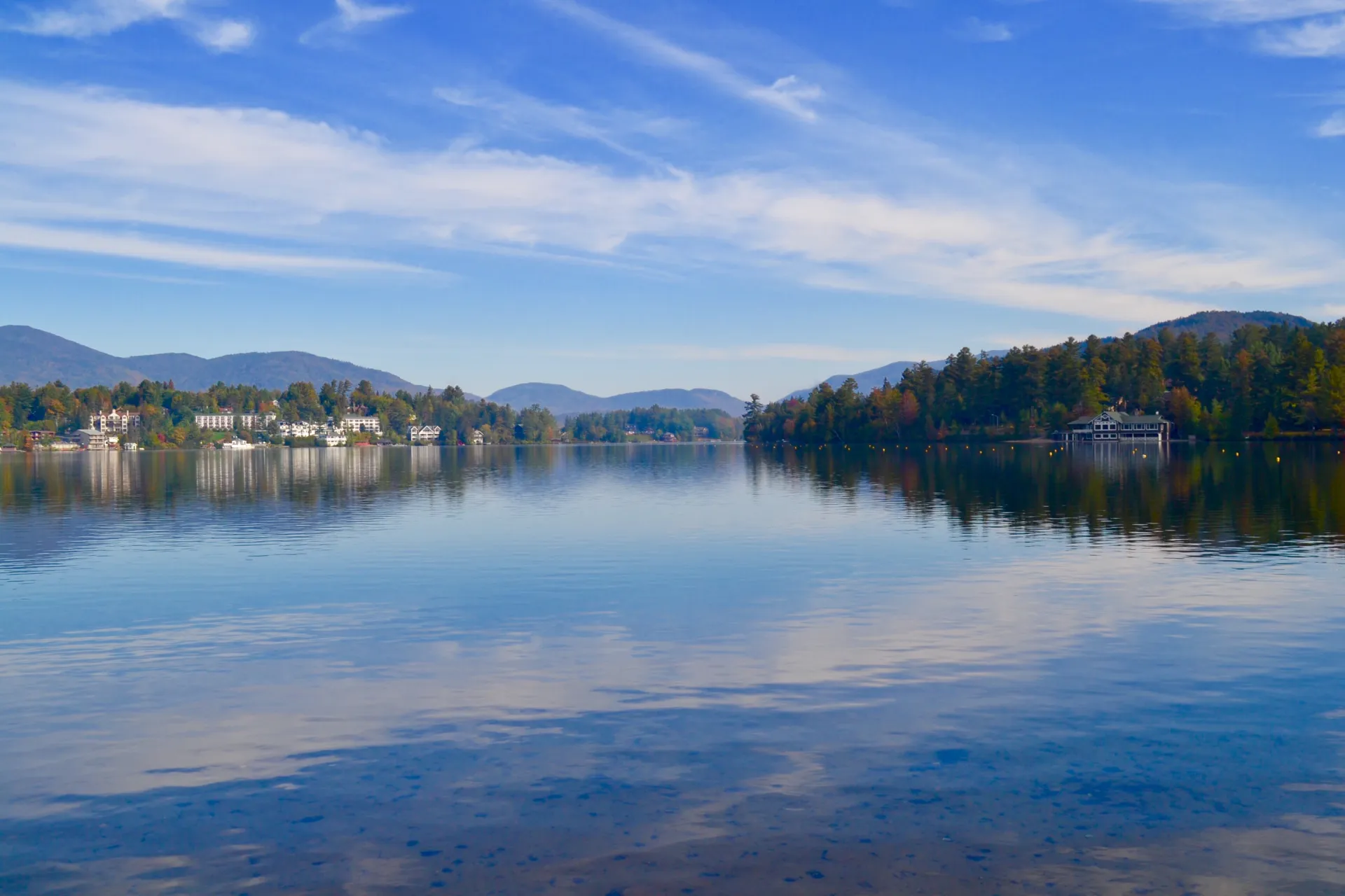 A lake reflects the partly-cloudy sky.