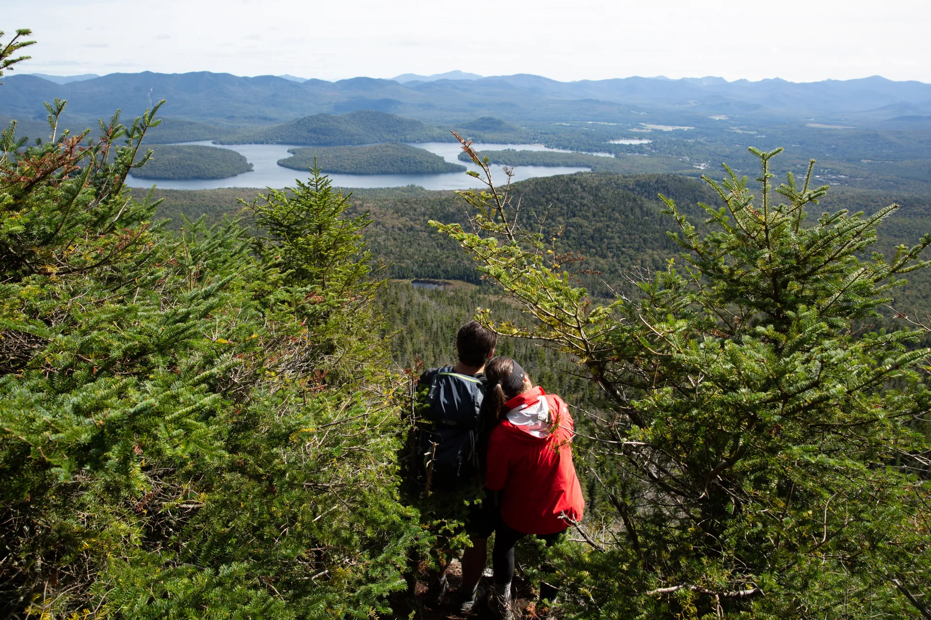 A couple poses with their back to the camera as they stare out from the summit of McKenzie Mountain