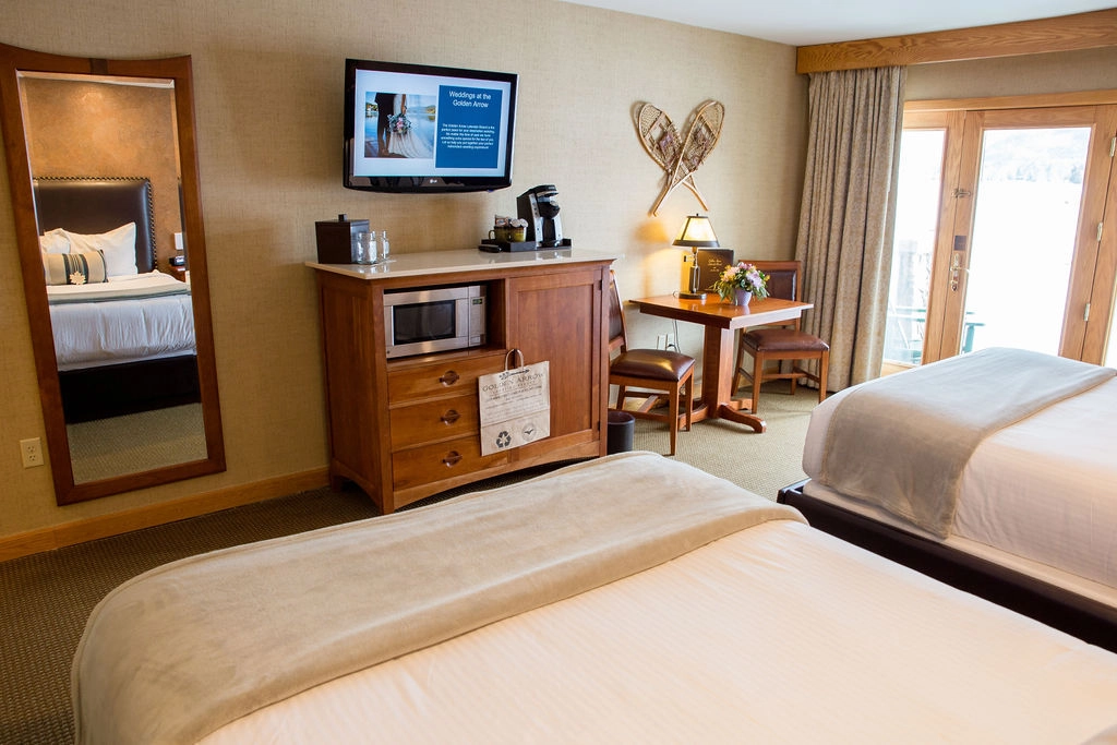 A wooden dresser under a wall mounted tv, with sitting area by the window.